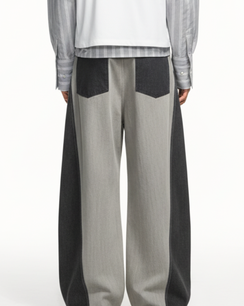 Rear view of Dual-Tone Curvilinear Denim Jeans in contrasting light and dark denim panels, featuring wide legs and back patch pockets, crafted with bespoke tailoring and a sculptural silhouette.