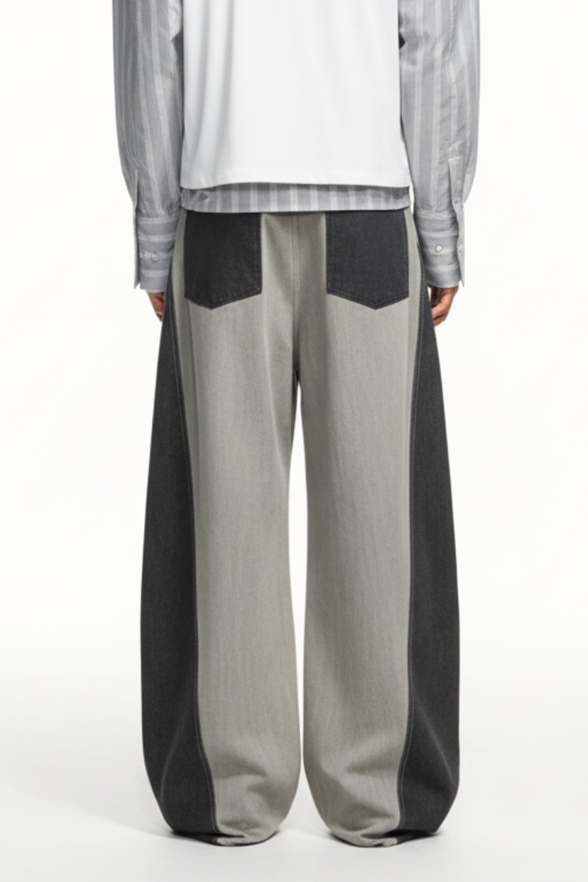 Rear view of Dual-Tone Curvilinear Denim Jeans in contrasting light and dark denim panels, featuring wide legs and back patch pockets, crafted with bespoke tailoring and a sculptural silhouette.