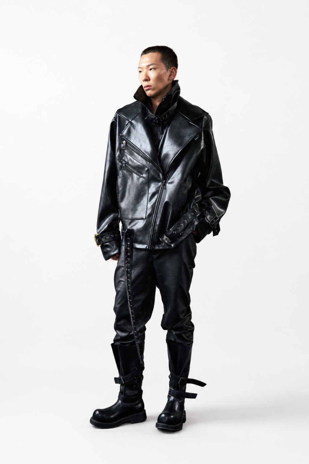 Full-length view of a model wearing the Vegan Leather Oversized Biker Coat in glossy black, featuring wide lapels, asymmetrical zippers, adjustable buckle straps, and a striking sculptural silhouette, paired with black pants and buckle boots, reflecting SHAO New York luxury designer fashion and New York designer tailoring.