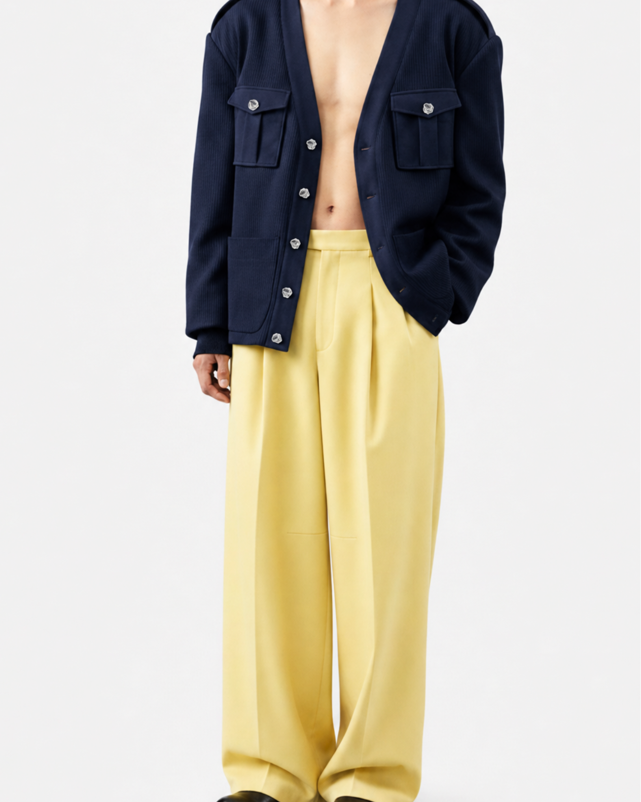 Model showcasing a Navy Military-Style Utility Cardigan with structured flap pockets and metal buttons, paired with wide-leg yellow trousers and black shoes, highlighting SHAO New York’s luxury designer fashion and sculptural silhouette.
