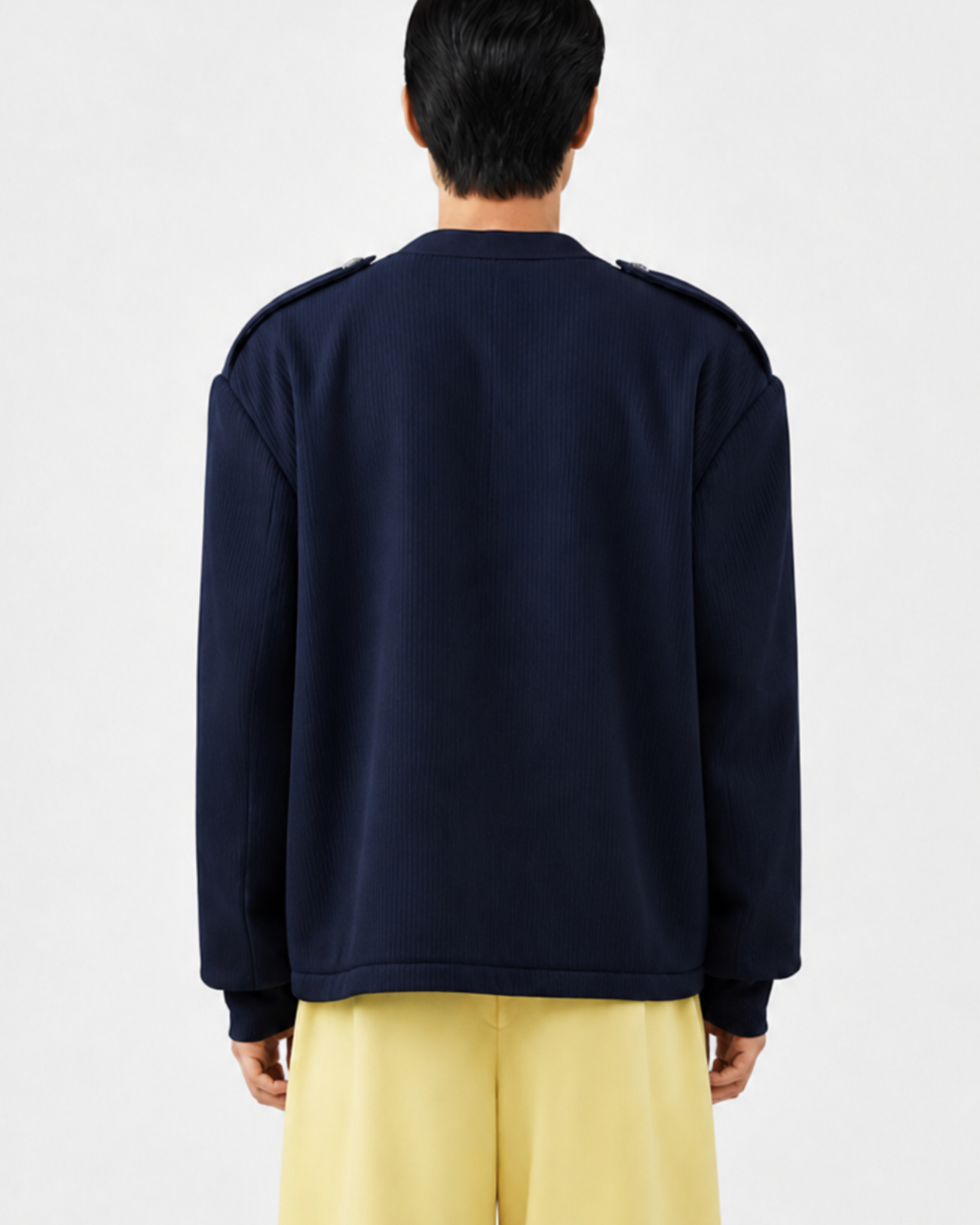 Back view of a model wearing a Navy Military-Style Utility Cardigan with structured shoulder epaulettes and a relaxed fit, paired with wide-leg yellow trousers for a refined sculptural silhouette.