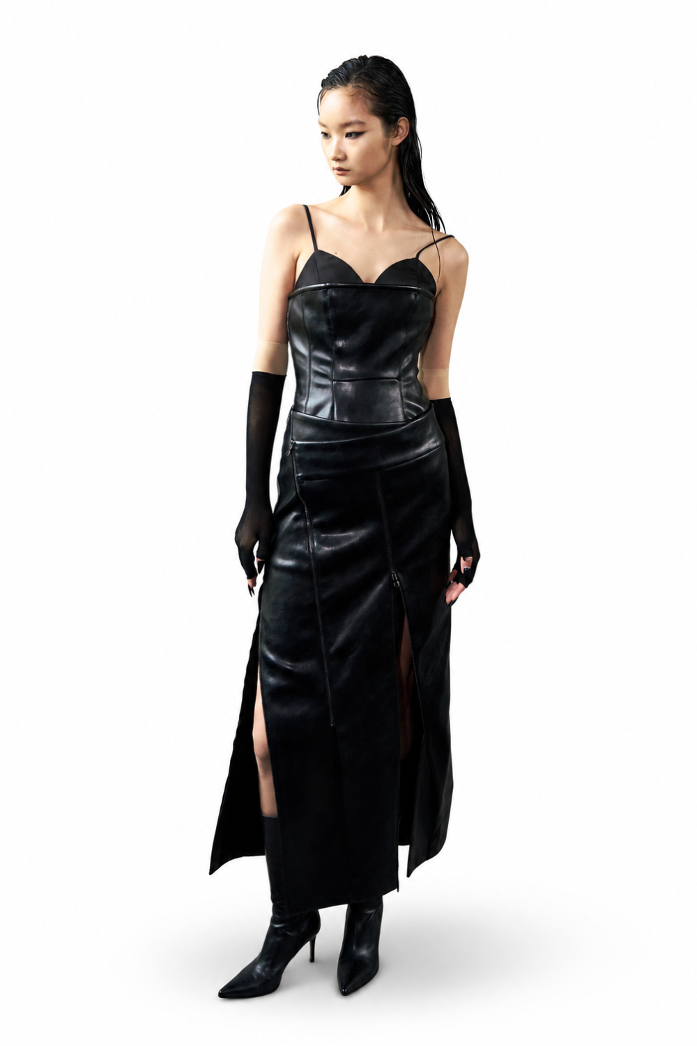 Model wearing the Vegan Leather Biker Dress in sleek black with thin straps, a structured bodice, a high slit, and paired with sheer black gloves and pointed boots, showcasing a sculptural silhouette.