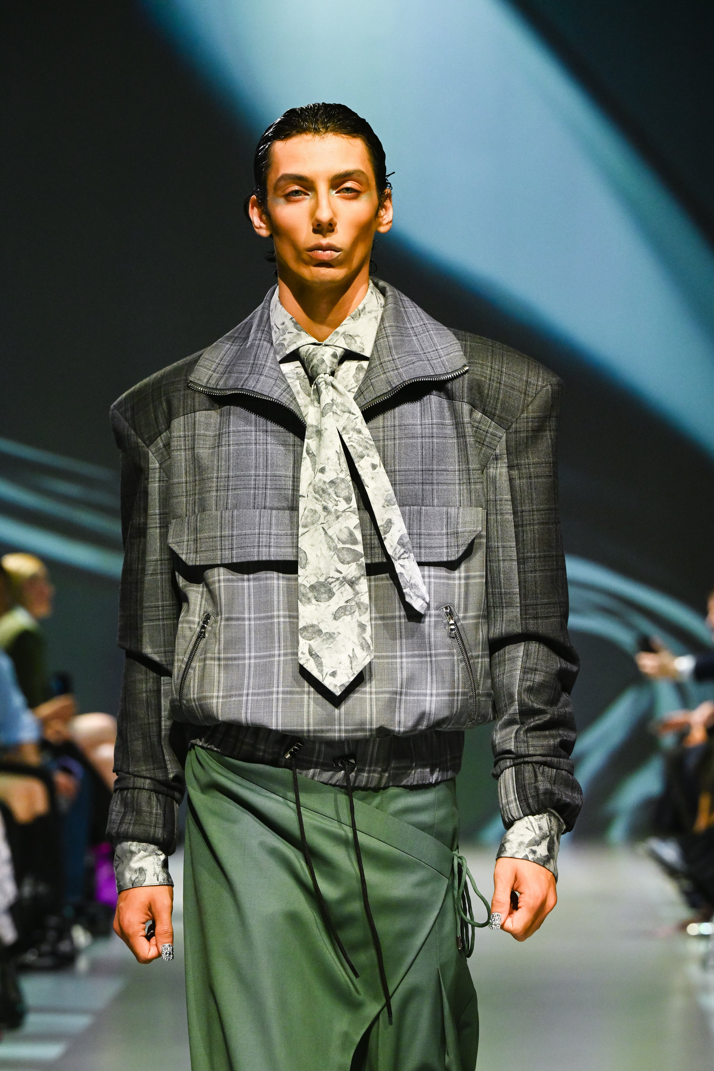 Model showcasing the White Baroque Floral Print Shirt styled with a tailored gray check jacket featuring sculptural shoulders and paired with a green draped skirt, representing SHAO New York luxury designer fashion and bespoke New York tailoring.
