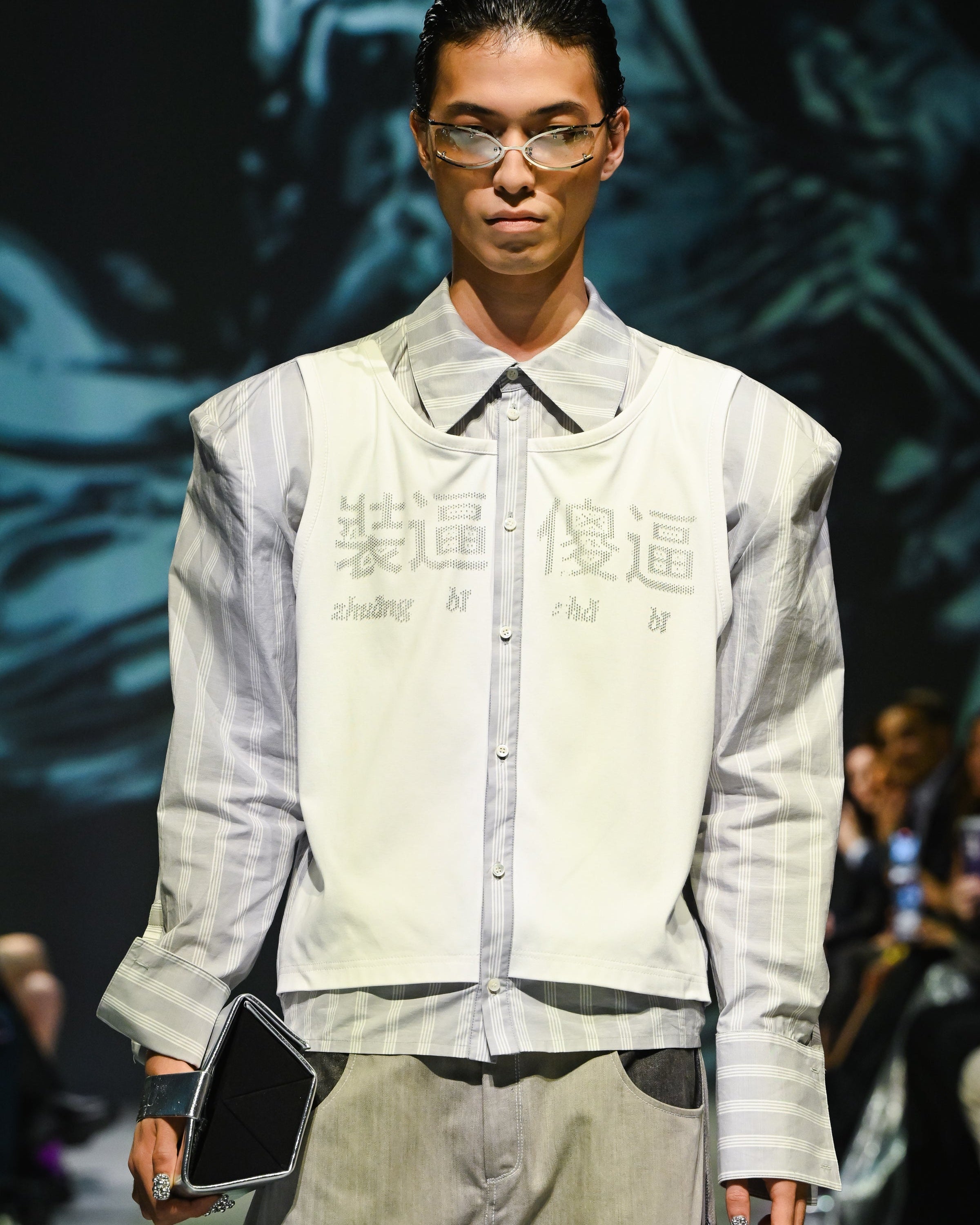 Model wearing Dual-Tone Curvilinear Denim Jeans paired with a striped shirt and sleeveless layered top, featuring a relaxed fit and modern sculptural silhouette in SHAO New York bespoke tailoring.