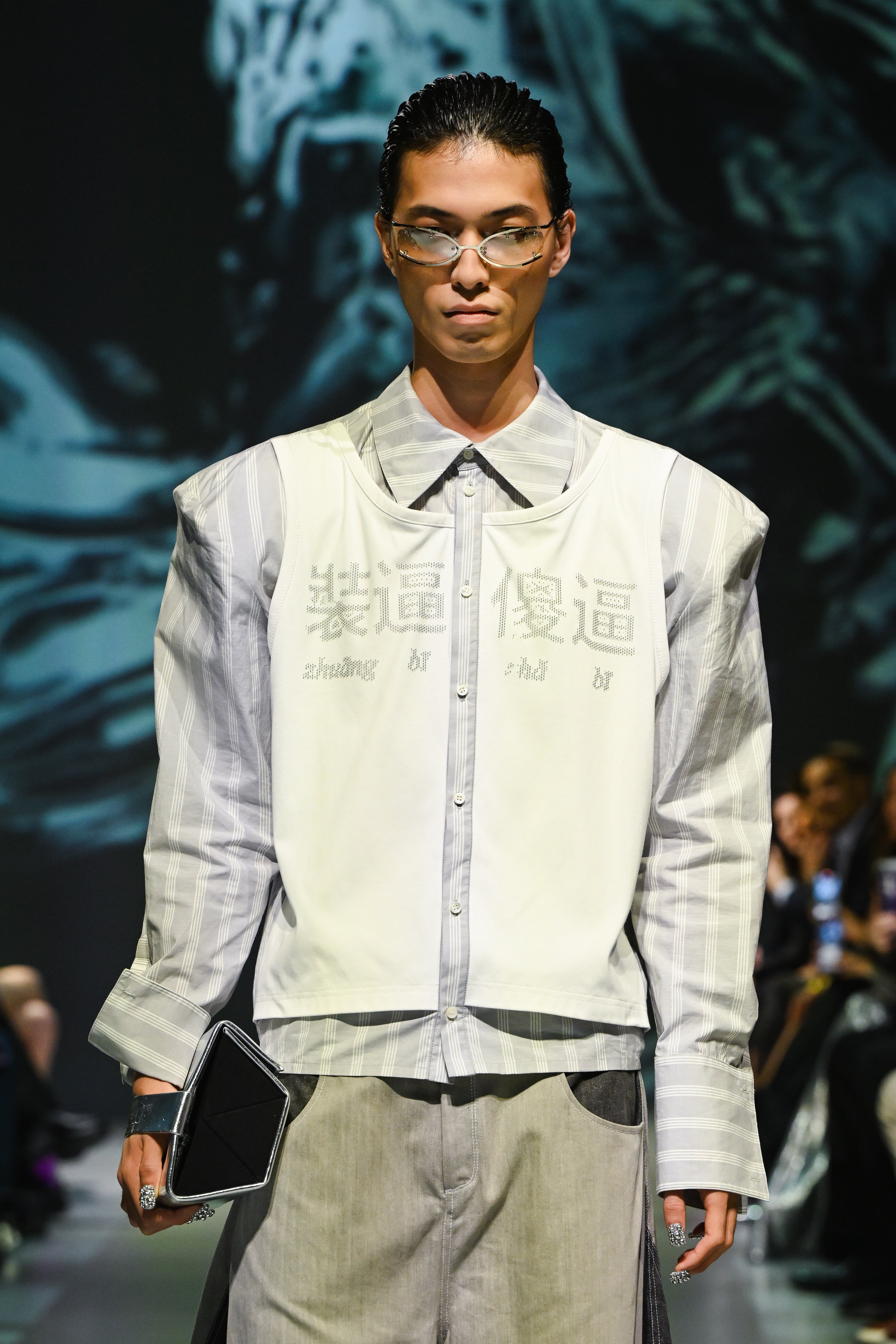 Model wearing Dual-Tone Curvilinear Denim Jeans paired with a striped shirt and sleeveless layered top, featuring a relaxed fit and modern sculptural silhouette in SHAO New York bespoke tailoring.