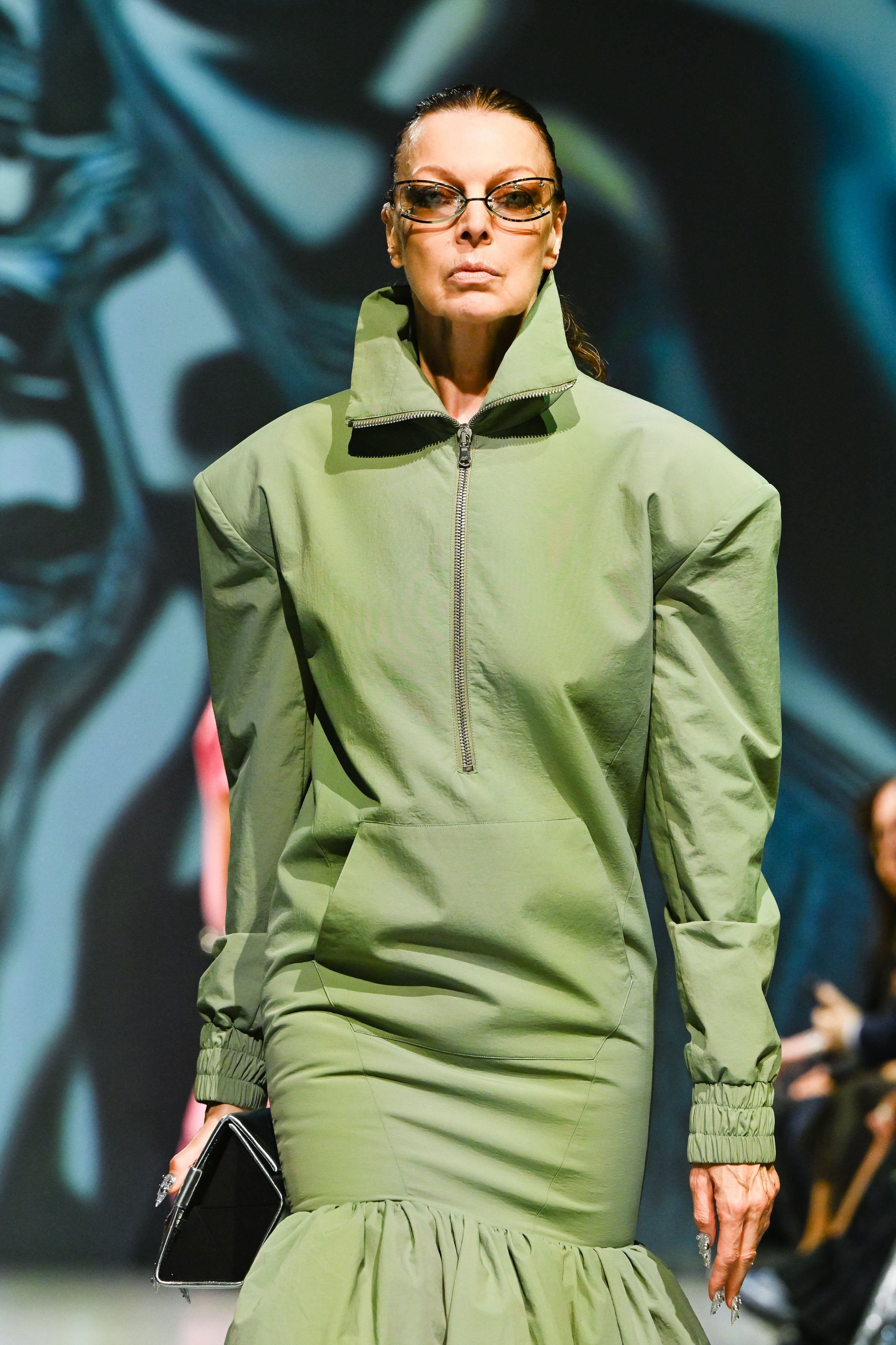 Model wearing Sage Green Utility Anorak Jacket Dress with structured shoulders, high collar zipper, elasticated cuffs, and gathered skirt, exemplifying bespoke New York tailoring by SHAO New York.