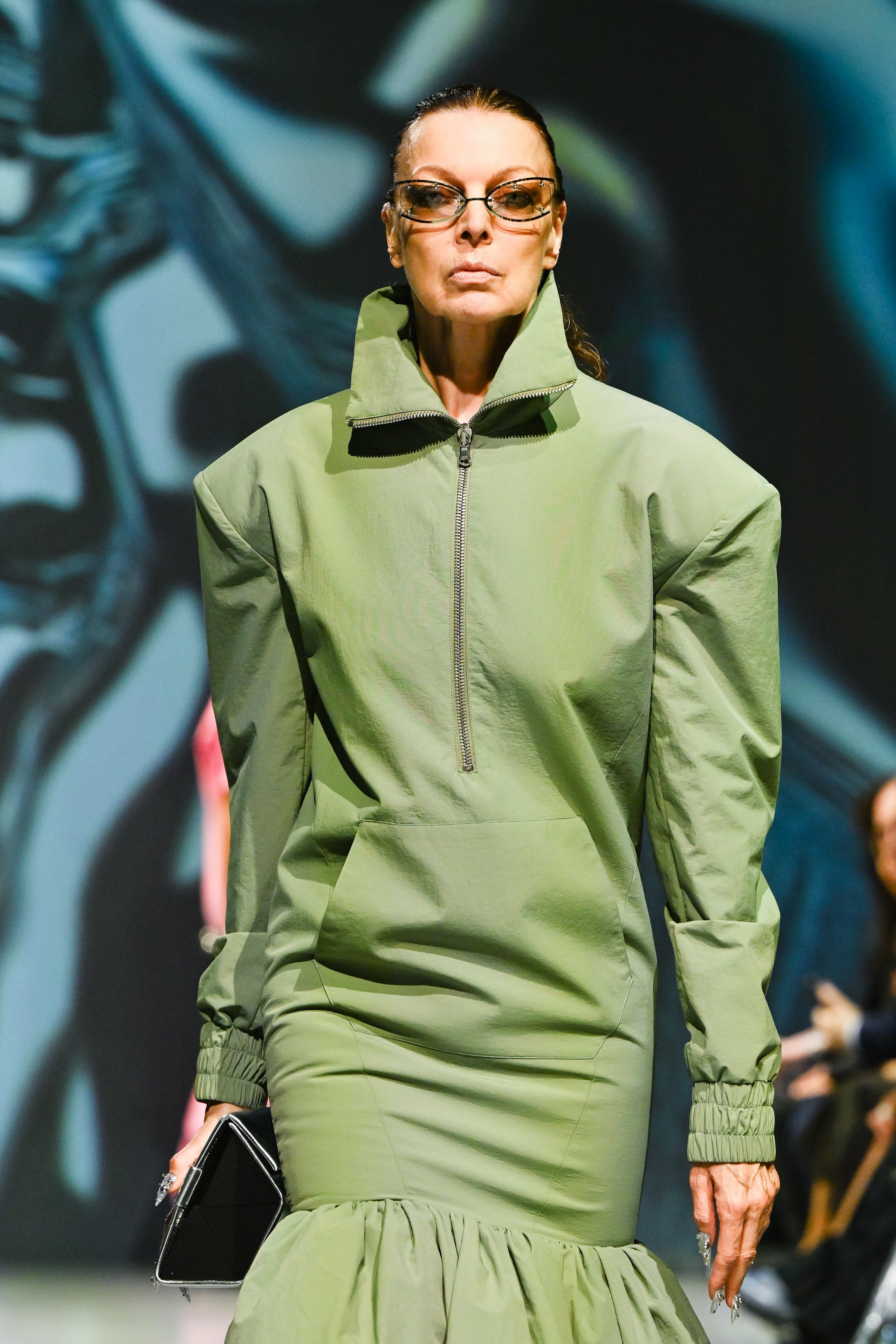 Model wearing Sage Green Utility Anorak Jacket Dress with structured shoulders, high collar zipper, elasticated cuffs, and gathered skirt, exemplifying bespoke New York tailoring by SHAO New York.