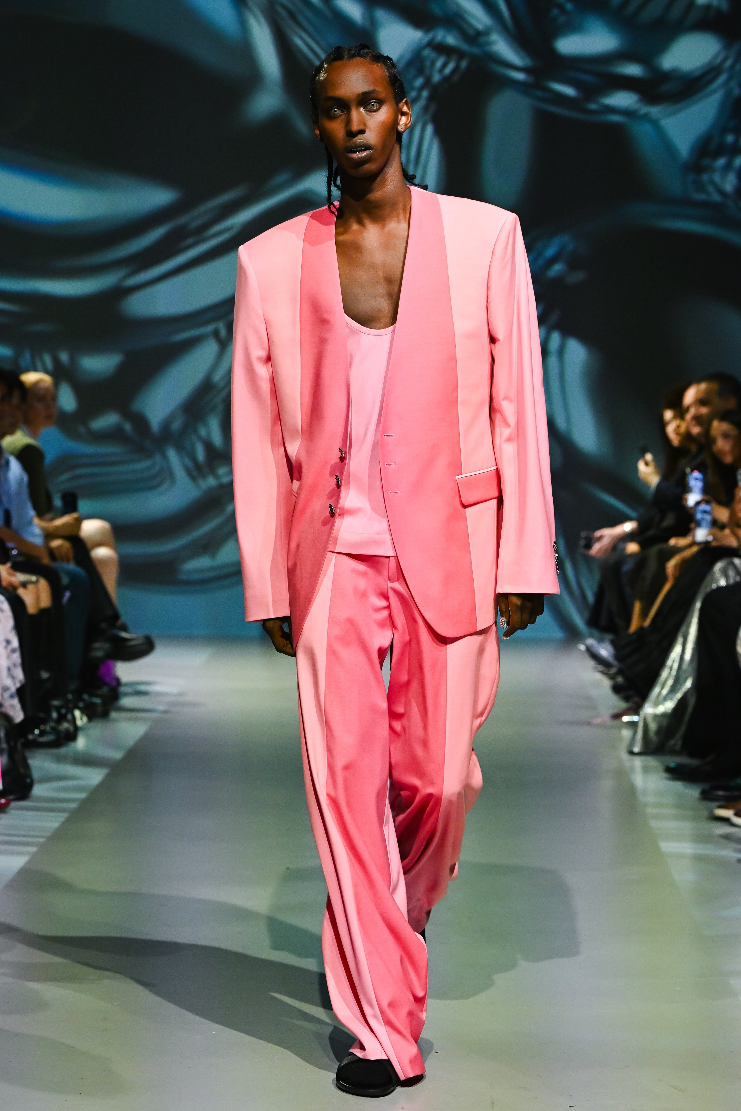 Model walking runway wearing a soft pink oversized blazer paired with Yellow Bi-Tonal Trousers featuring wide legs and a relaxed fit, showcasing luxurious bespoke tailoring by SHAO New York.