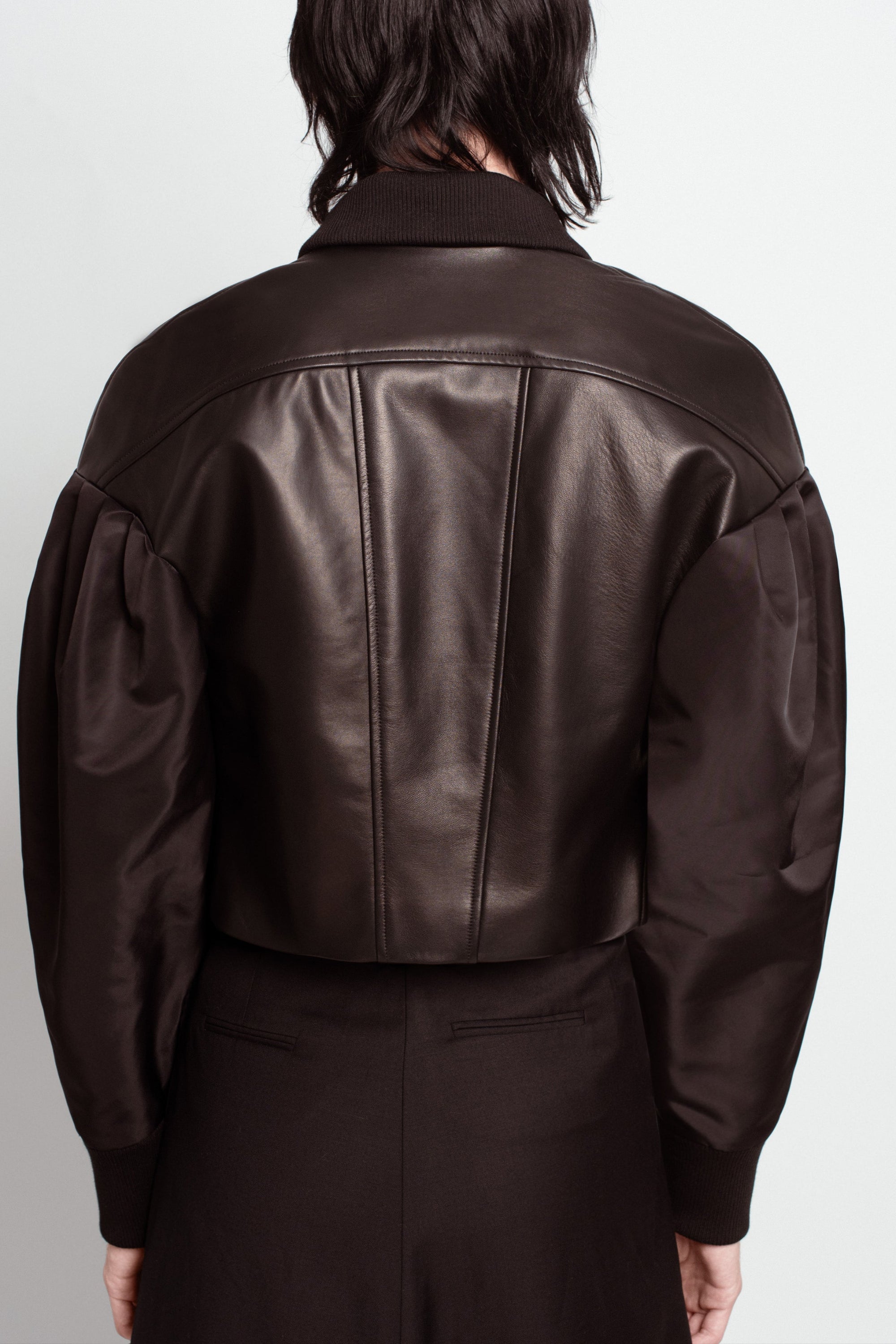 Back view of Jet Black Leather Bomber Jacket – Cropped Boxy Silhouette with mixed leather and satin textures, featuring a structured yoke, voluminous sleeves, and ribbed collar in SHAO New York luxury tailoring.
