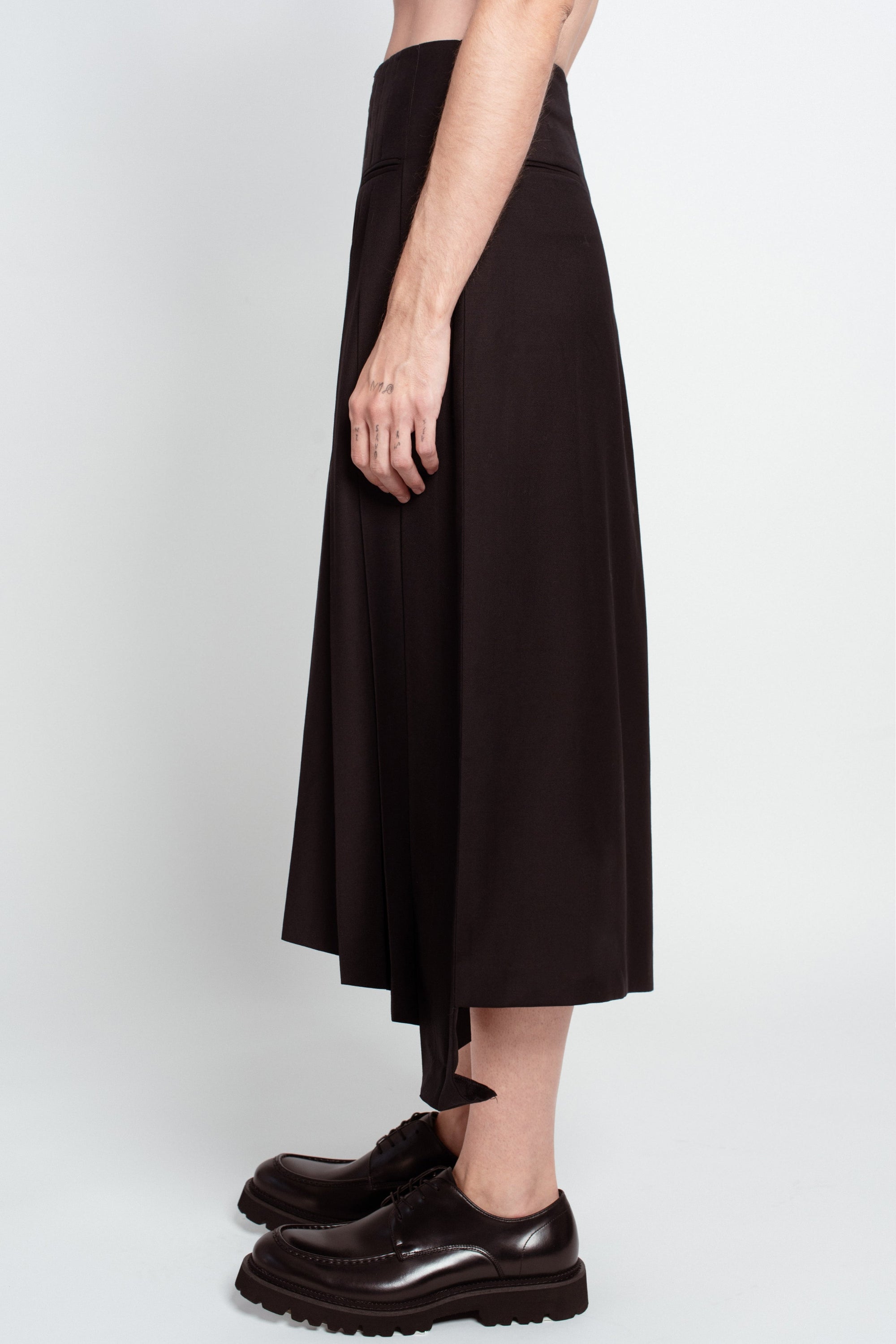 Side profile of Jet Black Wool Wrap Skirt – Pleated Long Silhouette with clean lines and subtle pleating, highlighting its sculptural shape in luxury designer fashion and bespoke New York tailoring.