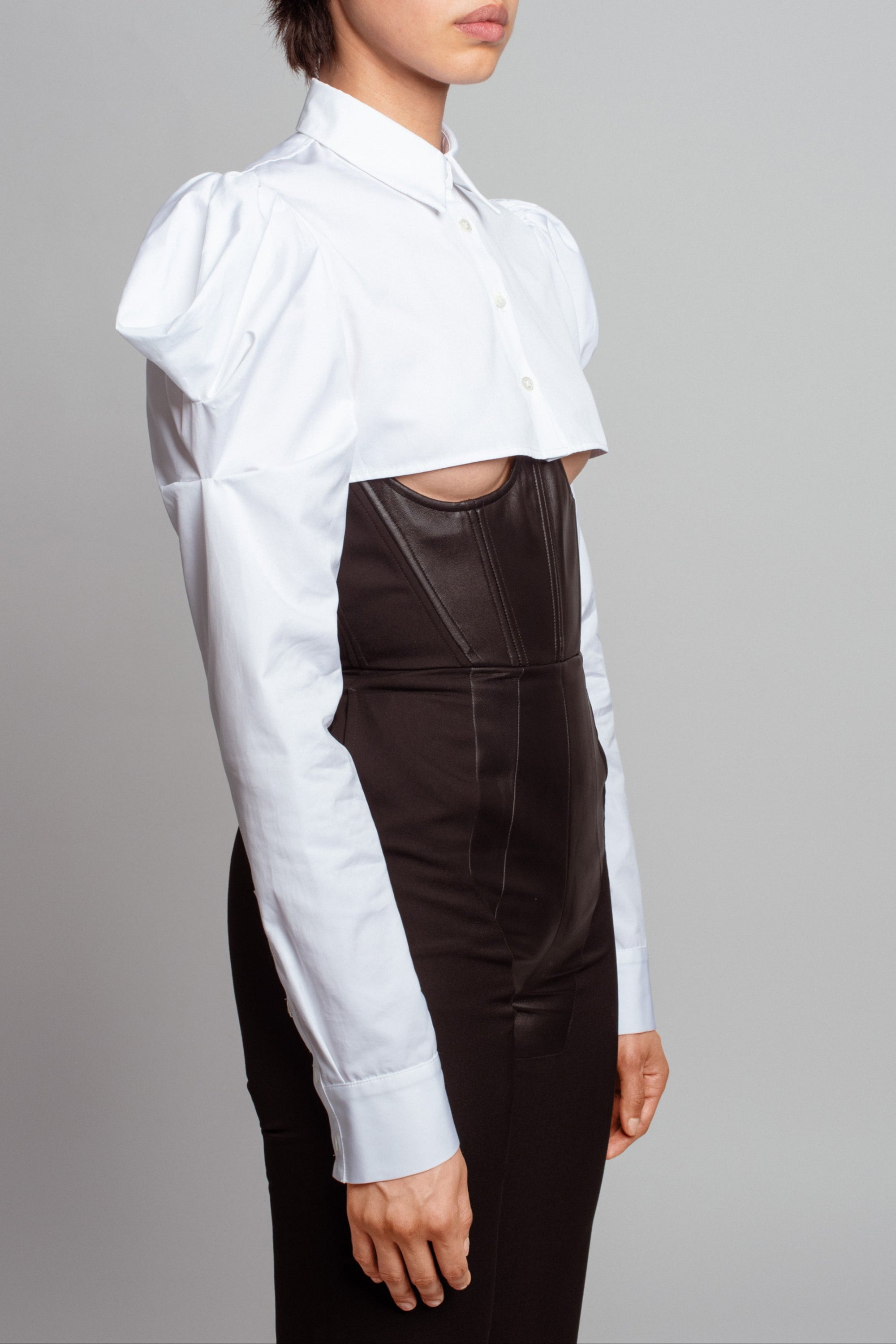 Side profile of Essential White Button-Up Shirt – Dramatic Puffed Shoulders, featuring a cropped silhouette with exaggerated puffed sleeves paired with sleek high-waist tailoring showcasing SHAO New York bespoke tailoring and luxury designer fashion.