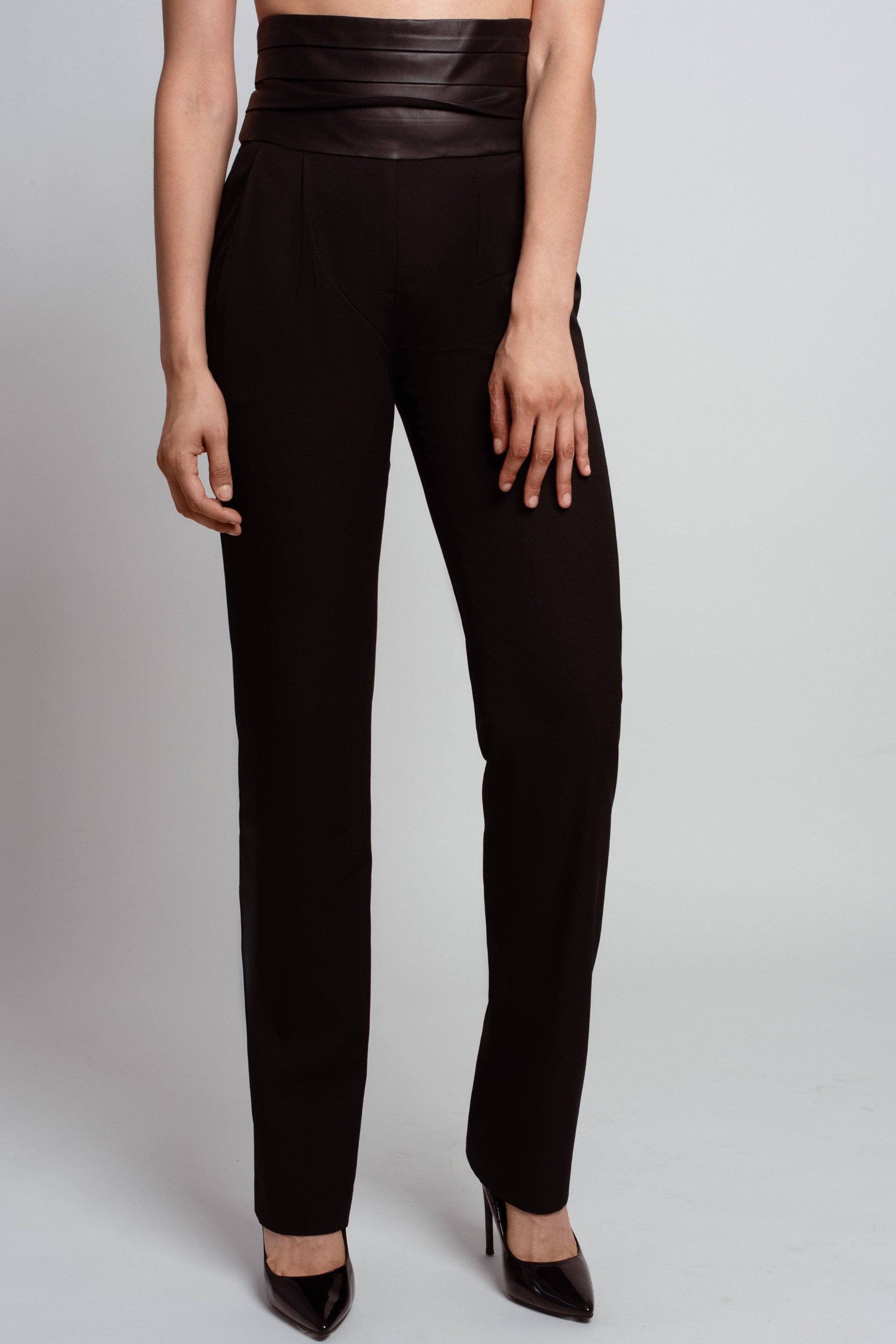 Front view of Jet Black Tailored Trousers – Leather Cummerbund Detail featuring a high-waisted leather waistband and a tailored slim leg silhouette in luxury designer fashion and bespoke New York tailoring.