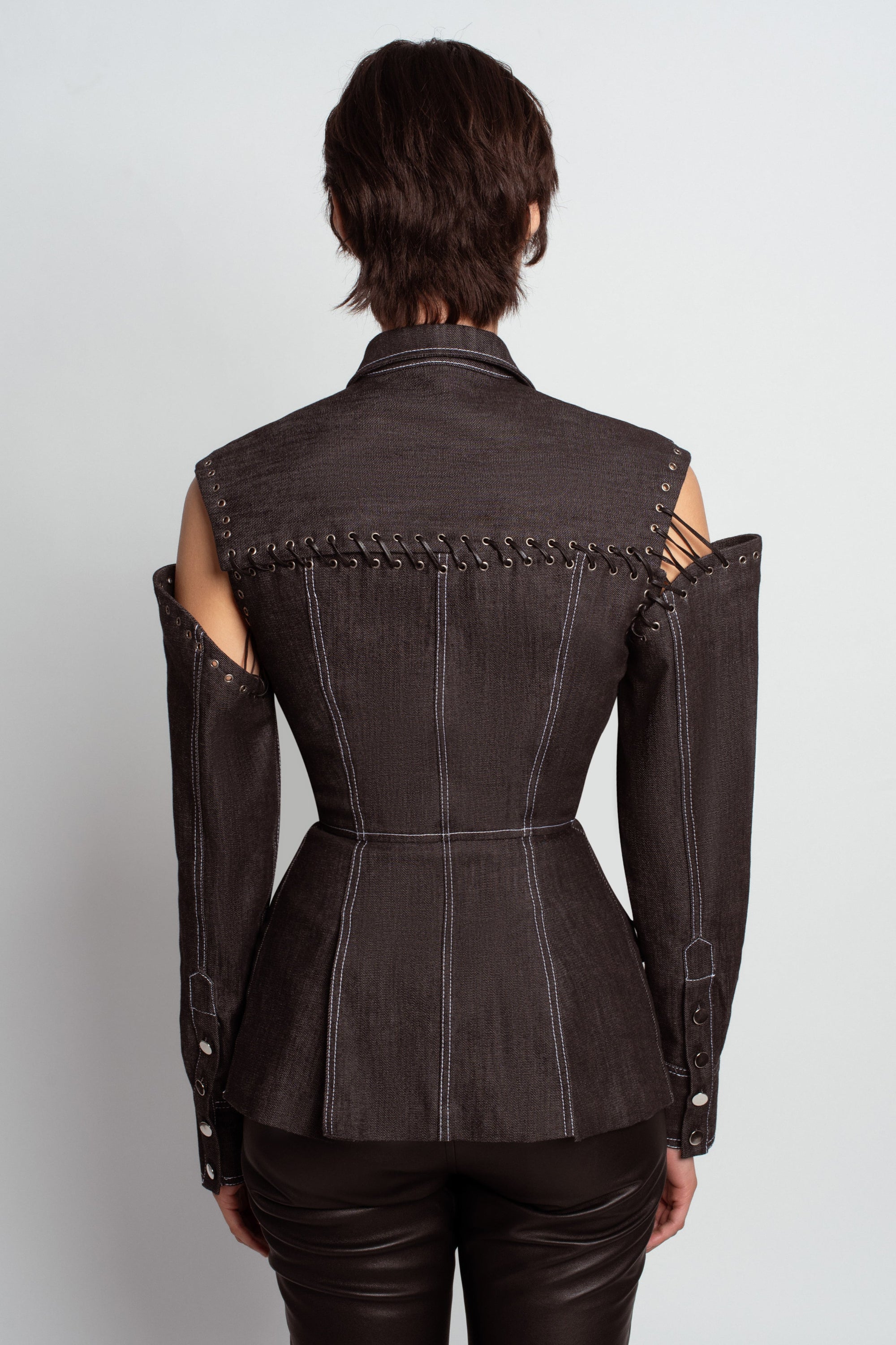 Back view of Midnight Blue Architectural Denim Jacket – Detachable Sleeve Design with exposed grommet and lacing details, tailored seams, and a structured waist creating a sculptural luxury silhouette.