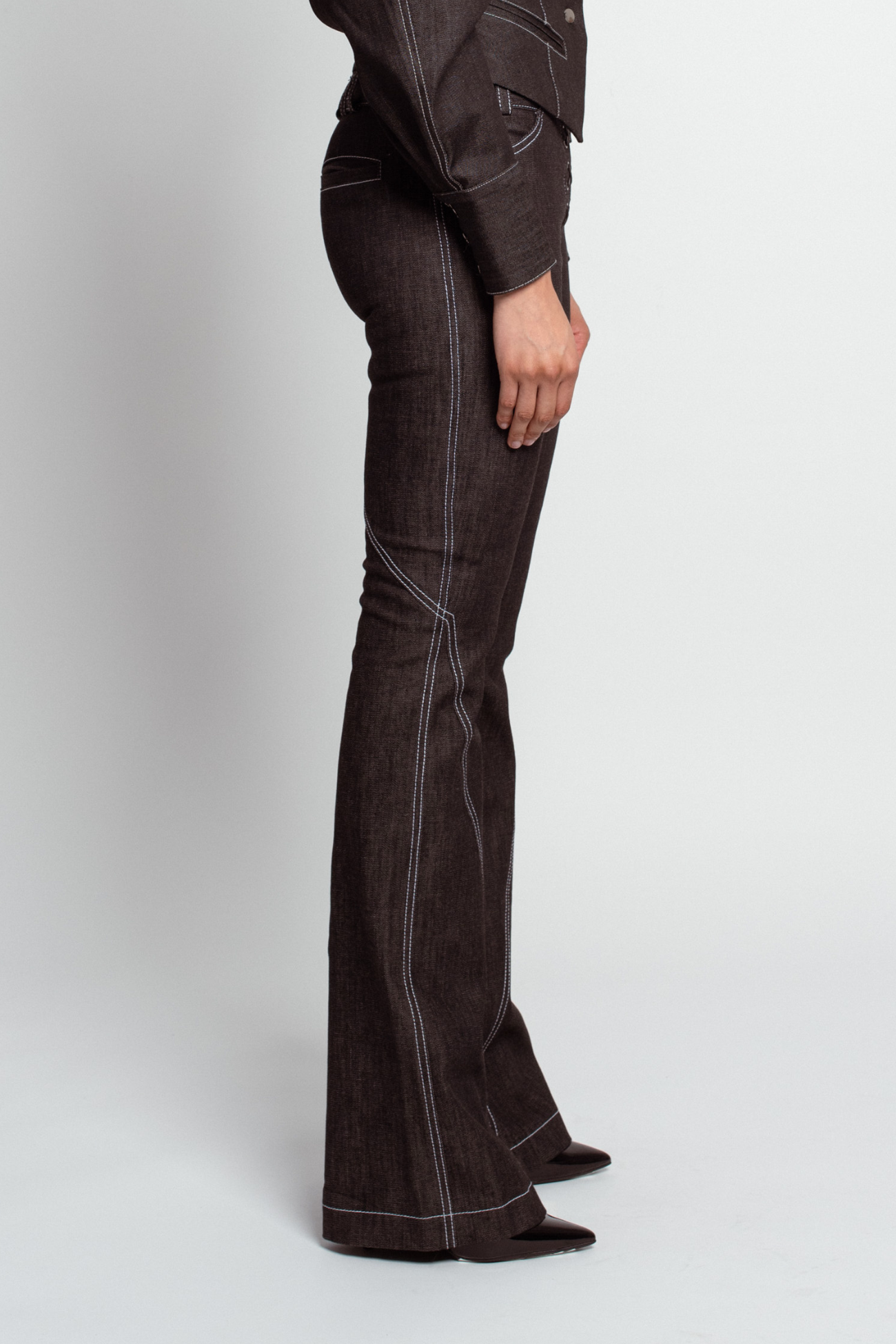 Dark Grey Lace-Up Flare Denim Trousers with visible contrast stitching, fitted through the hips and thighs, flaring elegantly from the knee, featuring a sculptural silhouette and tailored detailing.