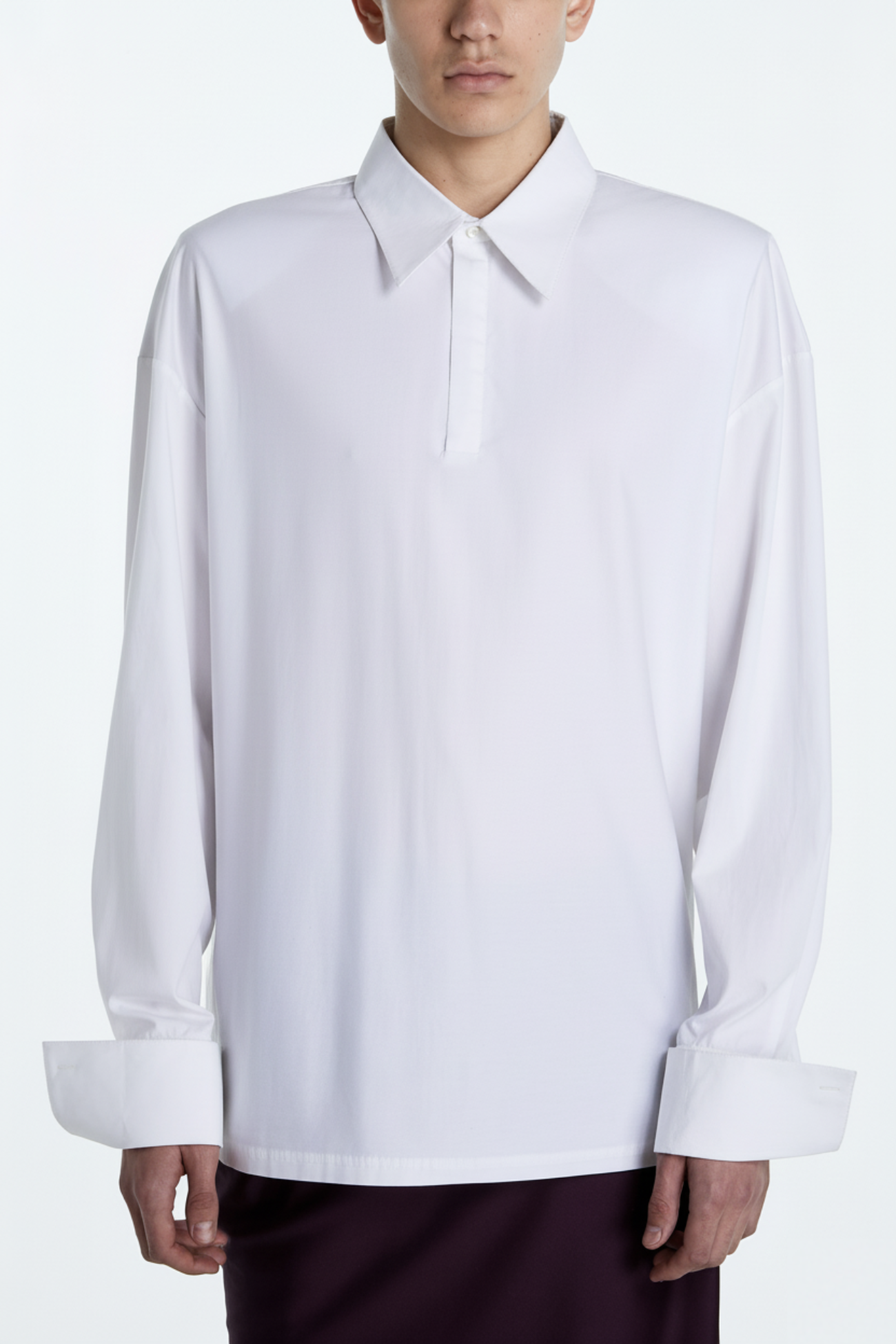 Model wearing an Architectural White Polo Shirt with an oversized fit, extended cuffs, and a minimalist pointed collar, highlighting modern New York designer tailoring.