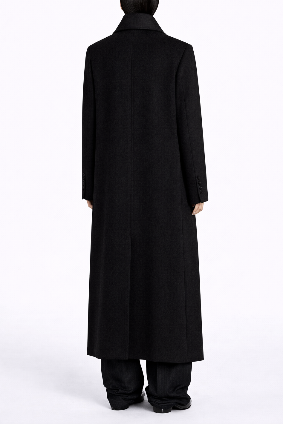 Person wearing a long black coat on a white background