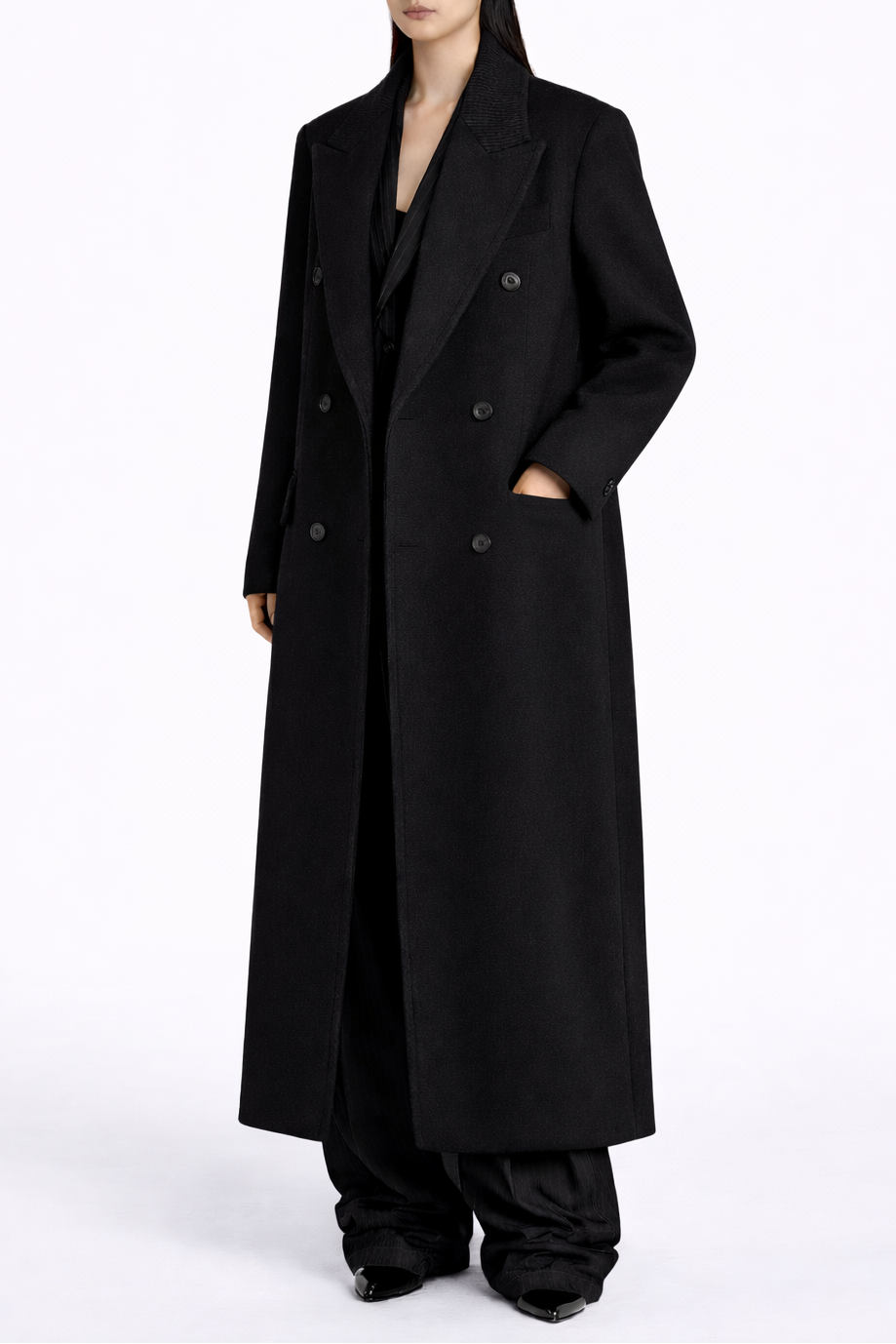 Person wearing a long black coat on a white background