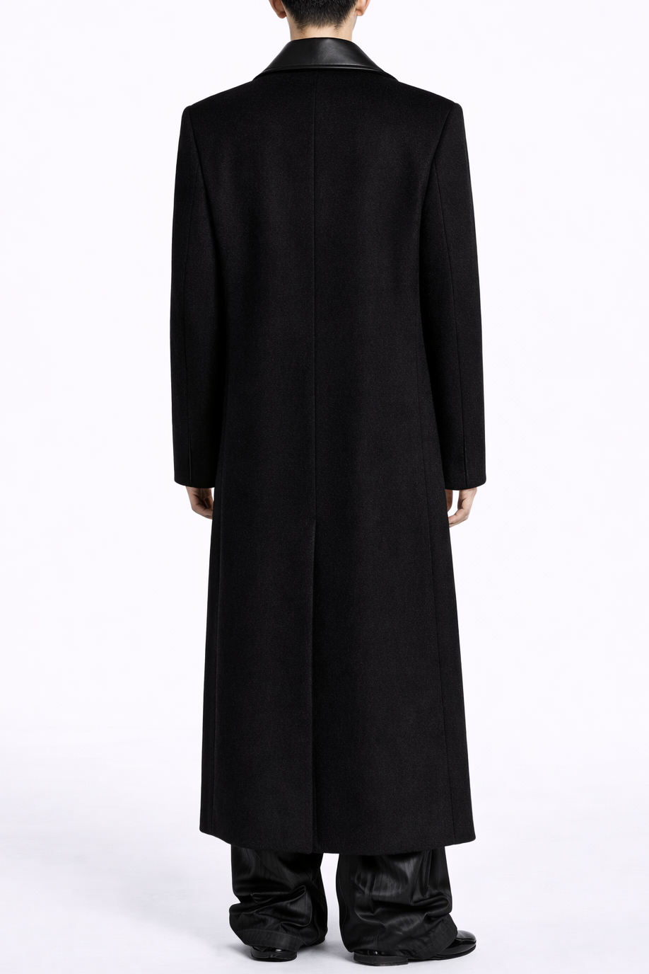Person wearing a long black coat on a white background