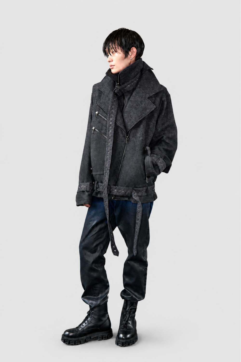 Model styled in black textured oversized jacket with multiple zippers and belted cuffs, paired with Drop-Crotch Denim Jeans with Leather Ombre Effect and chunky black lace-up boots creating a bold sculptural silhouette in luxury designer fashion.