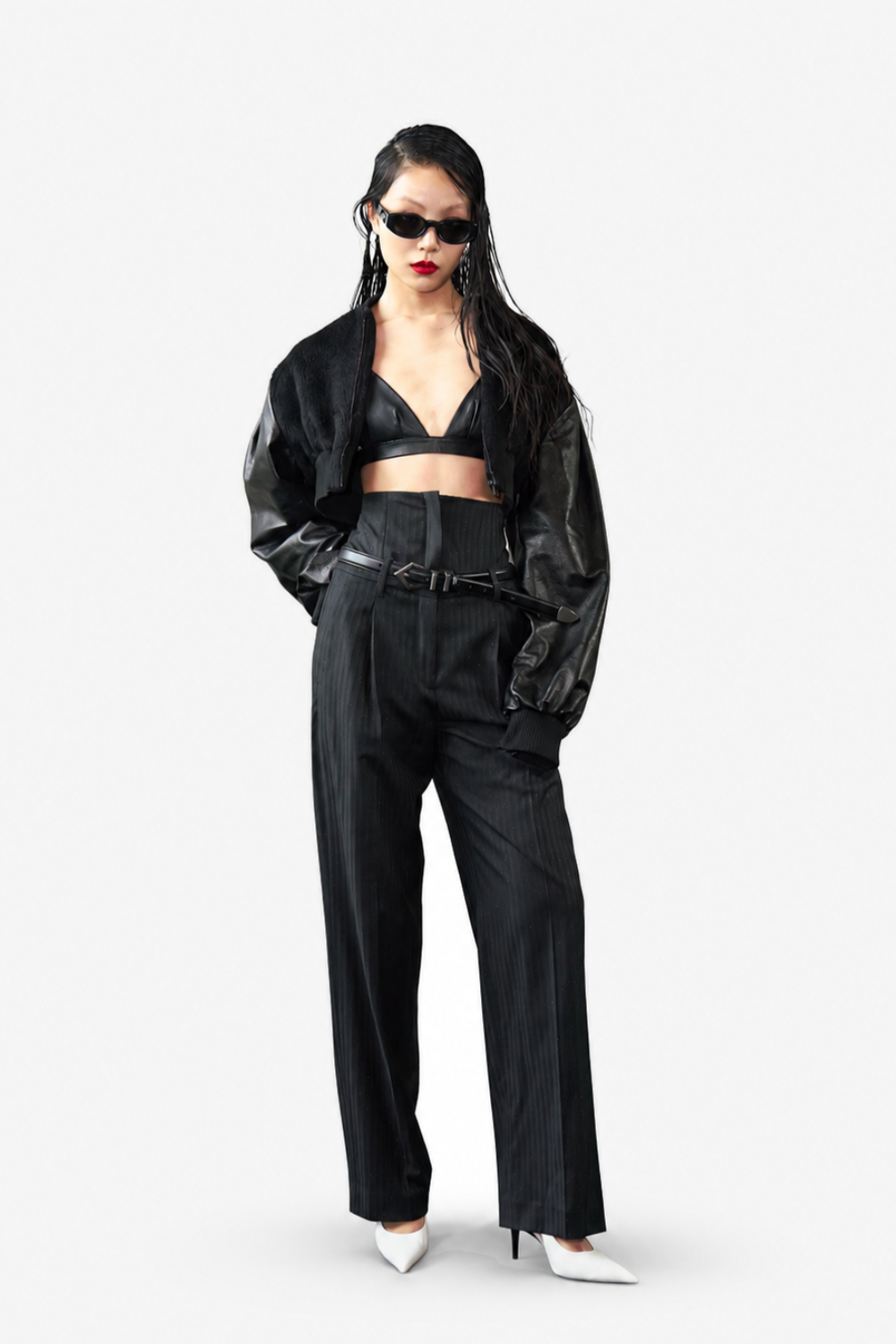 Model wearing the Cropped Alpaca and Leather Bomber Jacket styled with a black leather bralette, high-waisted pinstriped trousers, black belt, and white pointed heels, showcasing a bold sculptural silhouette and luxury bespoke tailoring.