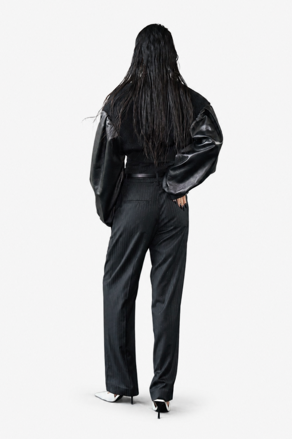 Back view of model wearing the Cropped Alpaca and Leather Bomber Jacket featuring voluminous leather sleeves paired with tailored black trousers and white pointed heels, highlighting a sculptural silhouette and bespoke tailoring.