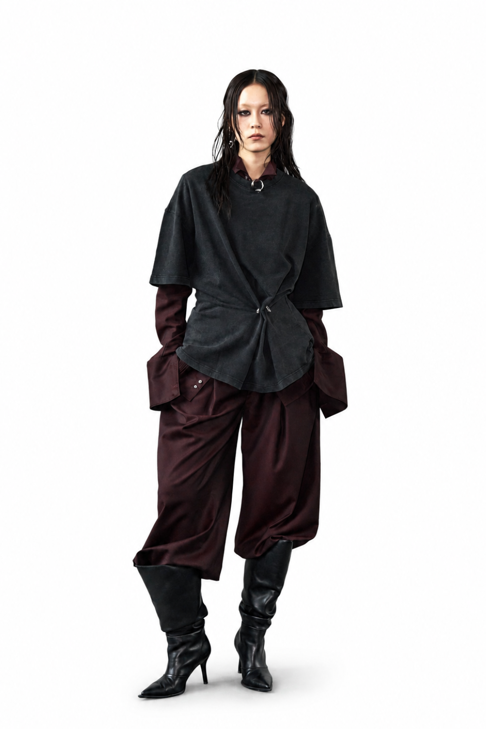 Model wearing Wool Barrel Pleated Trousers - Burgundy styled with layered dark tops featuring asymmetrical draping and oversized cuffs, paired with black pointed heeled boots, showcasing a sculptural silhouette with SHAO New York bespoke tailoring influences.