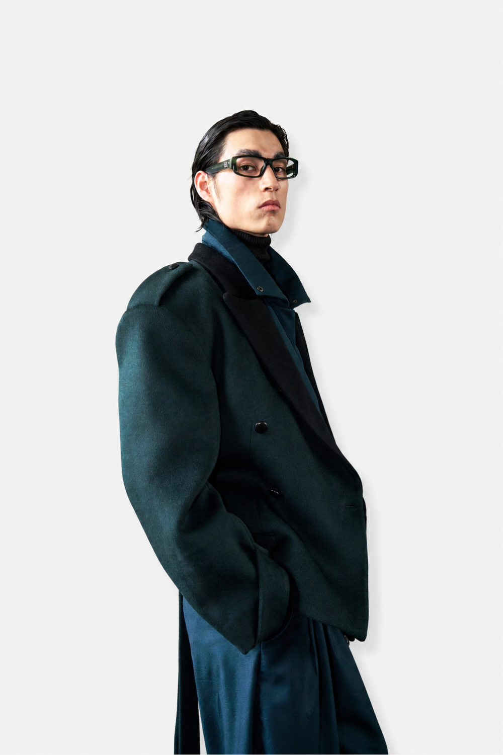 Model wearing Wool Barrel Pleated Trousers - Emerald styled with an oversized sculptural tailored coat featuring voluminous sleeves and a structured collar, showcasing SHAO New York bespoke tailoring and refined luxury designer fashion.