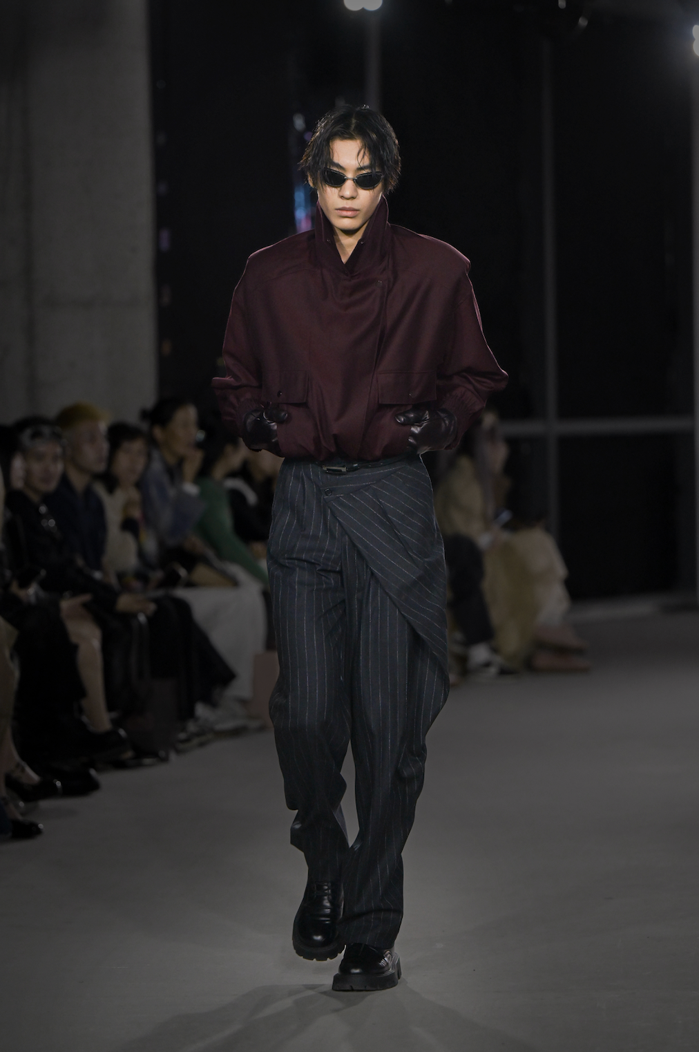 Model wearing Tailored Wool Balloon Bomber Jacket - Burgundy with a high collar and voluminous sleeves, styled with pinstriped asymmetrical trousers and black gloves, showcasing SHAO New York luxury designer fashion and a sculptural silhouette.