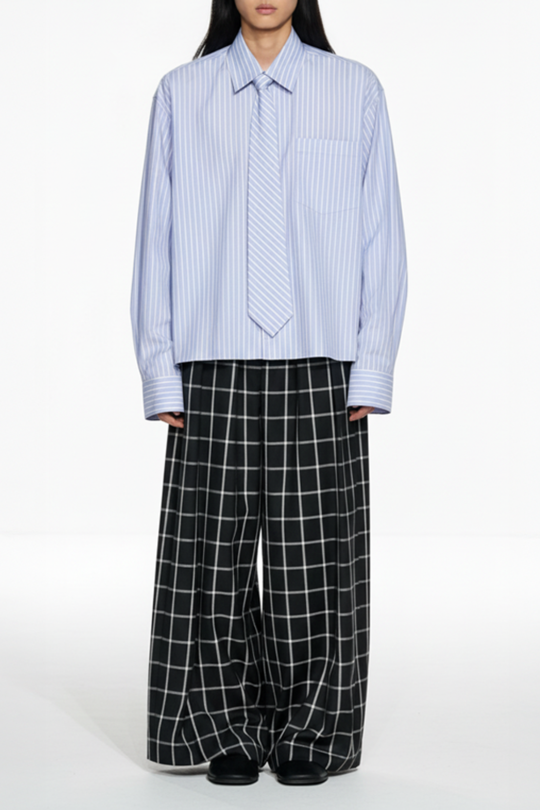 Front view of Windowpane Wide-Leg Double-Pleated Trousers featuring a bold black and white windowpane pattern, a flowing wide-leg silhouette, and precise bespoke tailoring by SHAO New York.
