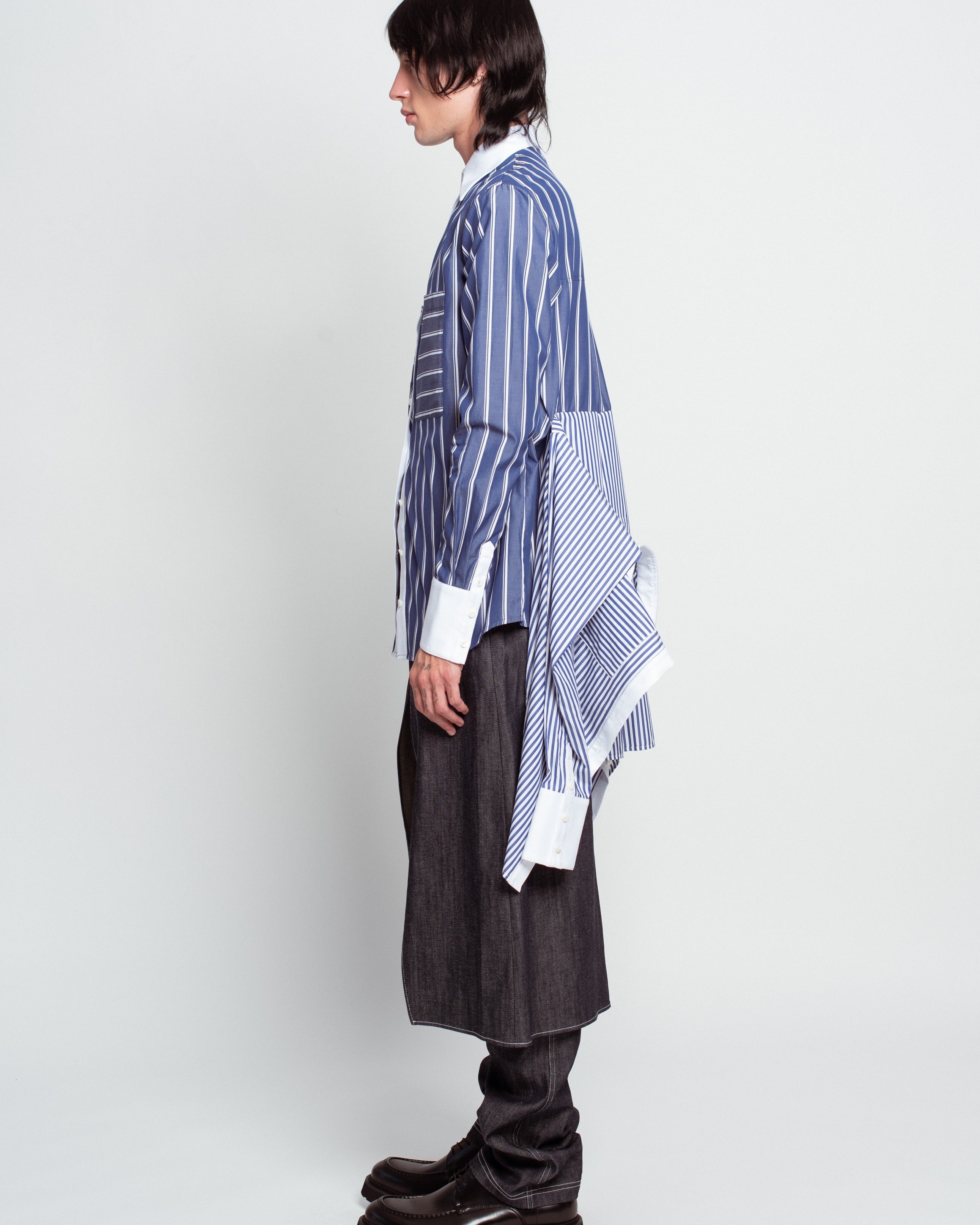 Side profile of Blue Pinstripe Layered Shirt – Attached Back Construction featuring mixed vertical and horizontal stripes, sharp white cuffs, and an avant-garde sculptural back detail exemplifying SHAO New York bespoke tailoring and luxury designer fashion.