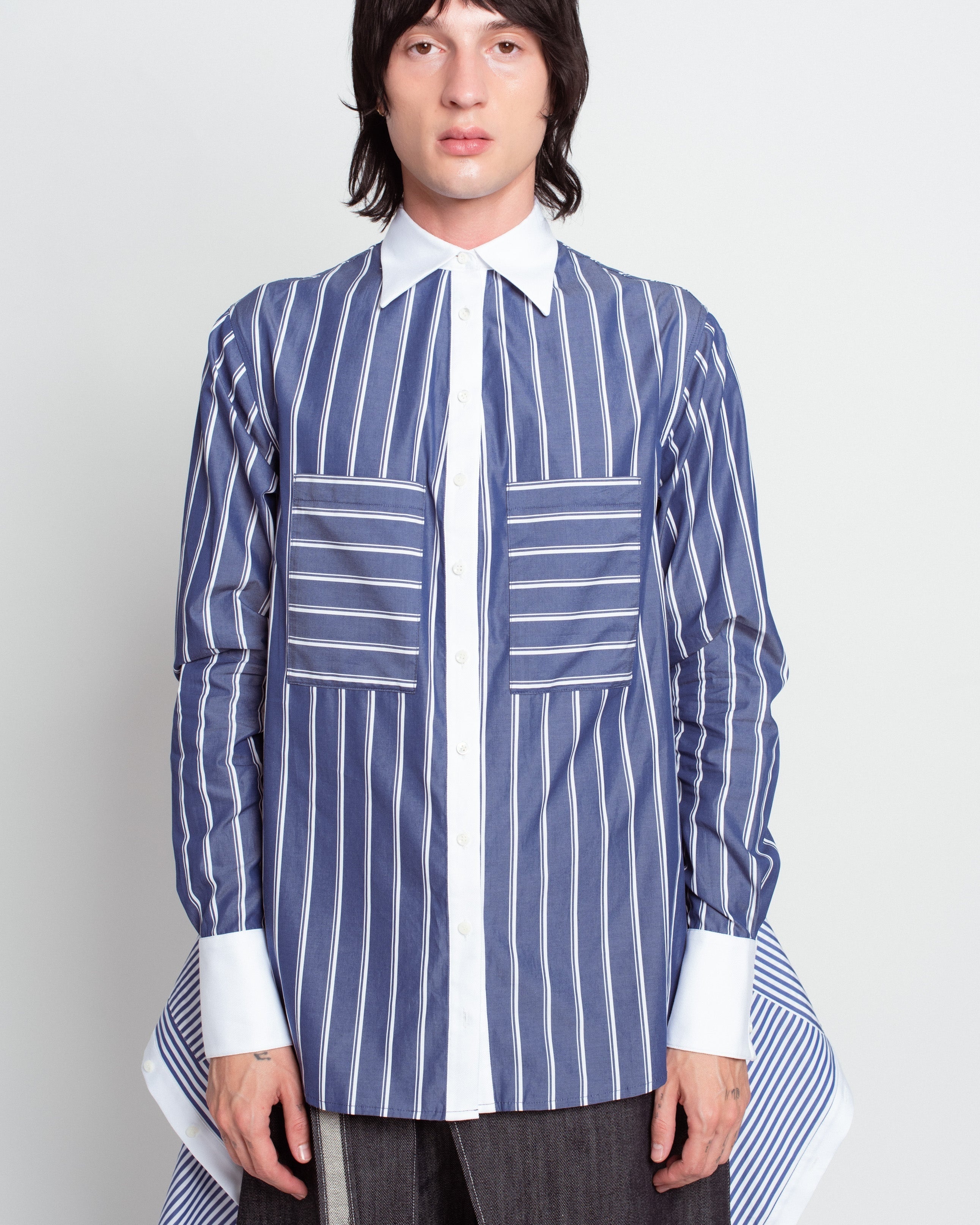 Front view of Blue Pinstripe Layered Shirt – Attached Back Construction in navy with vertical and horizontal white stripes, contrasted by crisp white collar and cuffs, featuring oversized patch pockets and layered detailing, showcasing SHAO New York bespoke tailoring and luxury designer fashion with a sculptural silhouette.