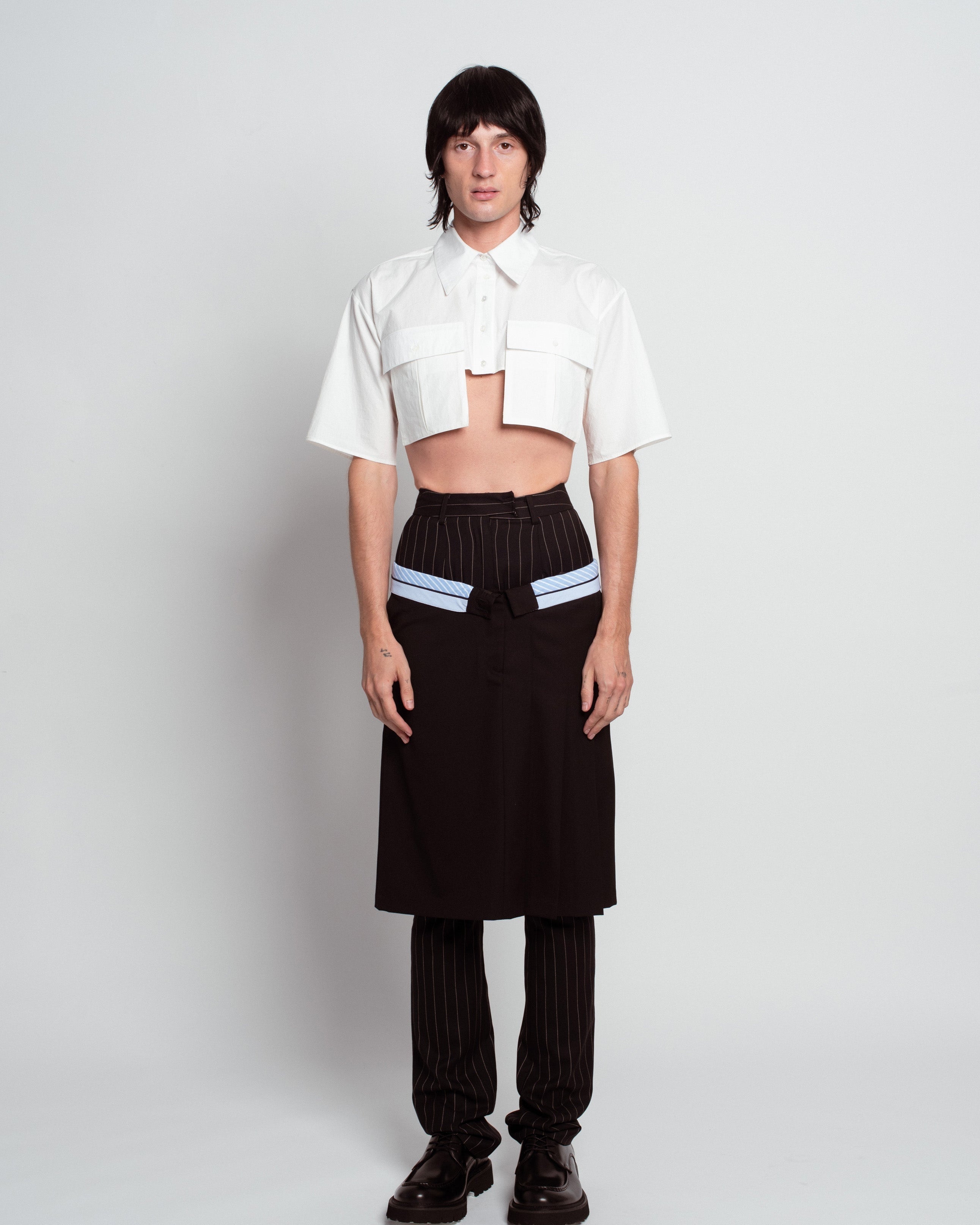 Front view of White Cropped Utility Shirt with short sleeves and flap pockets, styled with pinstriped trousers and a black wrap skirt, showcasing SHAO New York bespoke tailoring and luxury designer fashion.
