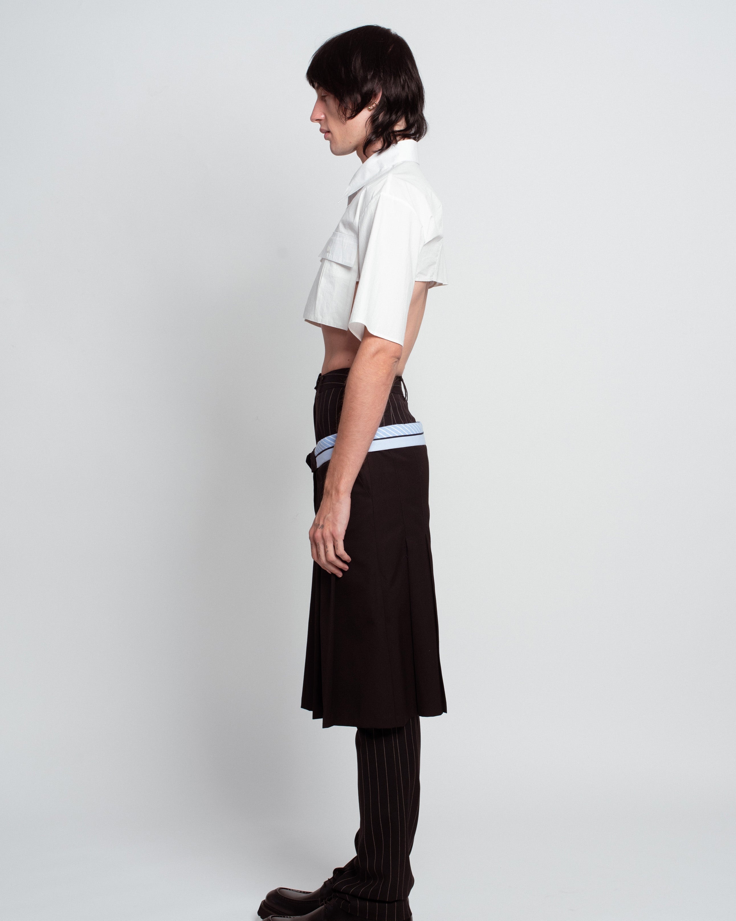 Side view of White Cropped Utility Shirt featuring short sleeves and flap chest pockets, styled with layered tailored trousers and a sculptural silhouette reflecting SHAO New York bespoke tailoring and luxury designer fashion.