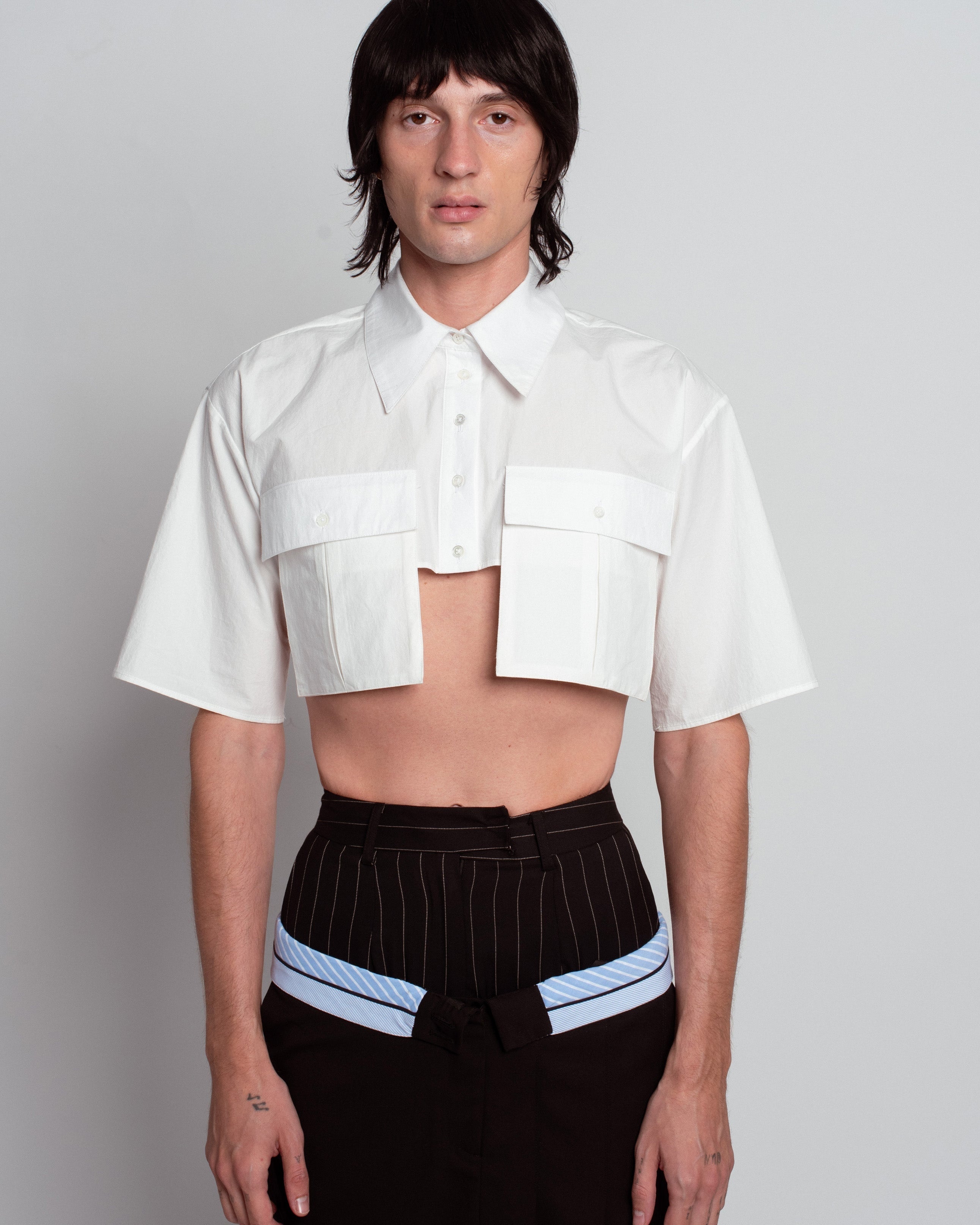 Front view of White Cropped Utility Shirt featuring a pointed collar, short sleeves, button closure, and oversized flap pockets, styled to highlight bespoke tailoring and luxury designer fashion.