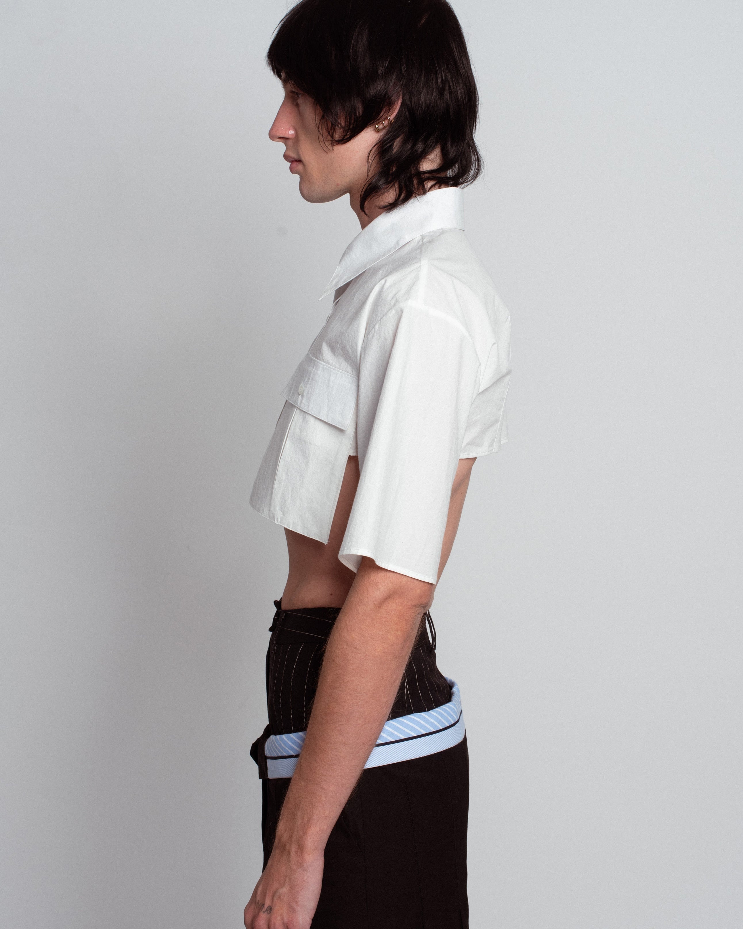 Side profile of White Cropped Utility Shirt with short sleeves and flap chest pockets, paired with pinstriped trousers, exemplifying SHAO New York bespoke tailoring and luxury designer fashion.