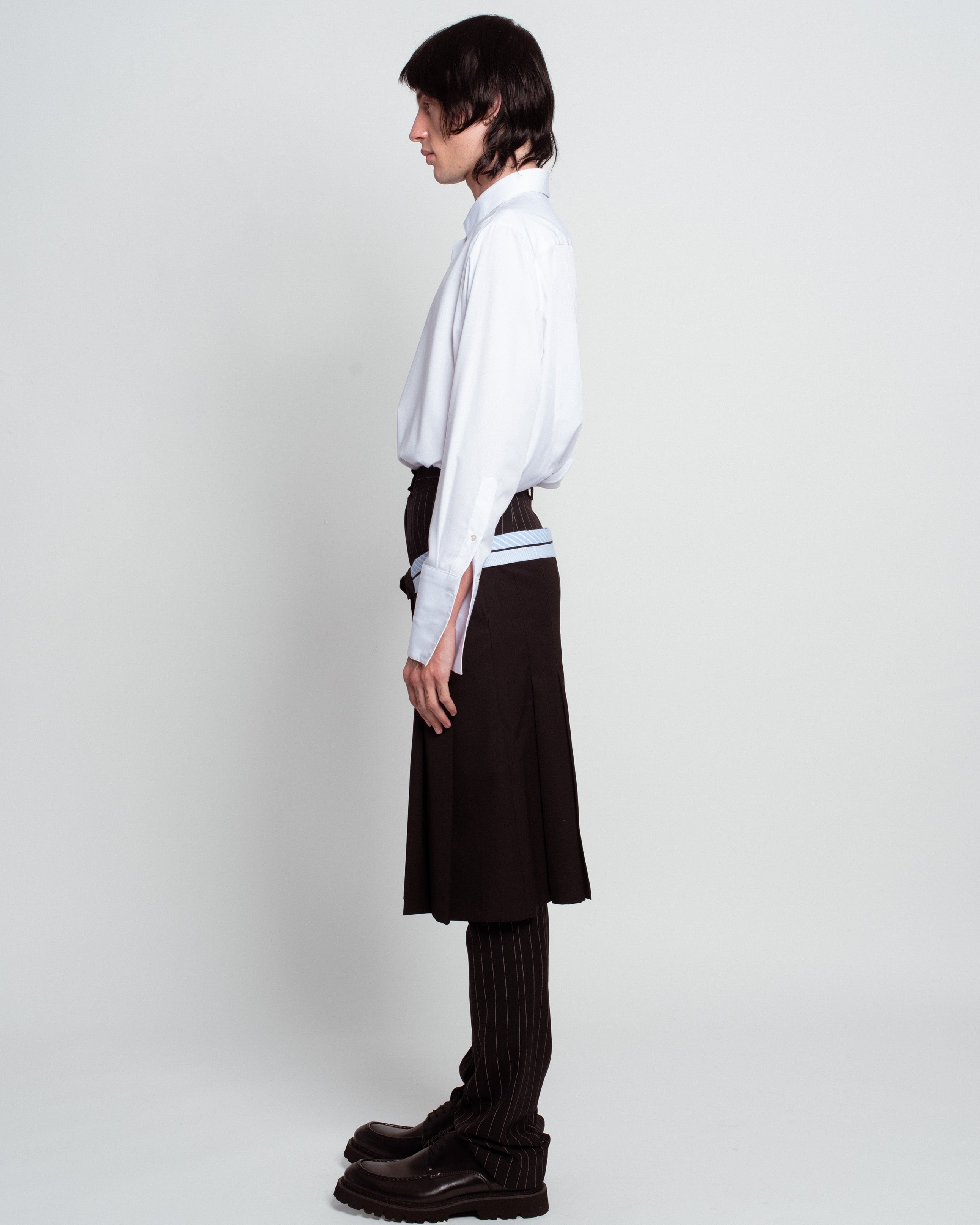 Profile view of White Classic Button-Down Shirt featuring a crisp collar, relaxed fit, long sleeves with buttoned cuffs, styled with layered tailored trousers for a sculptural silhouette reflecting SHAO New York bespoke tailoring and luxury designer fashion.