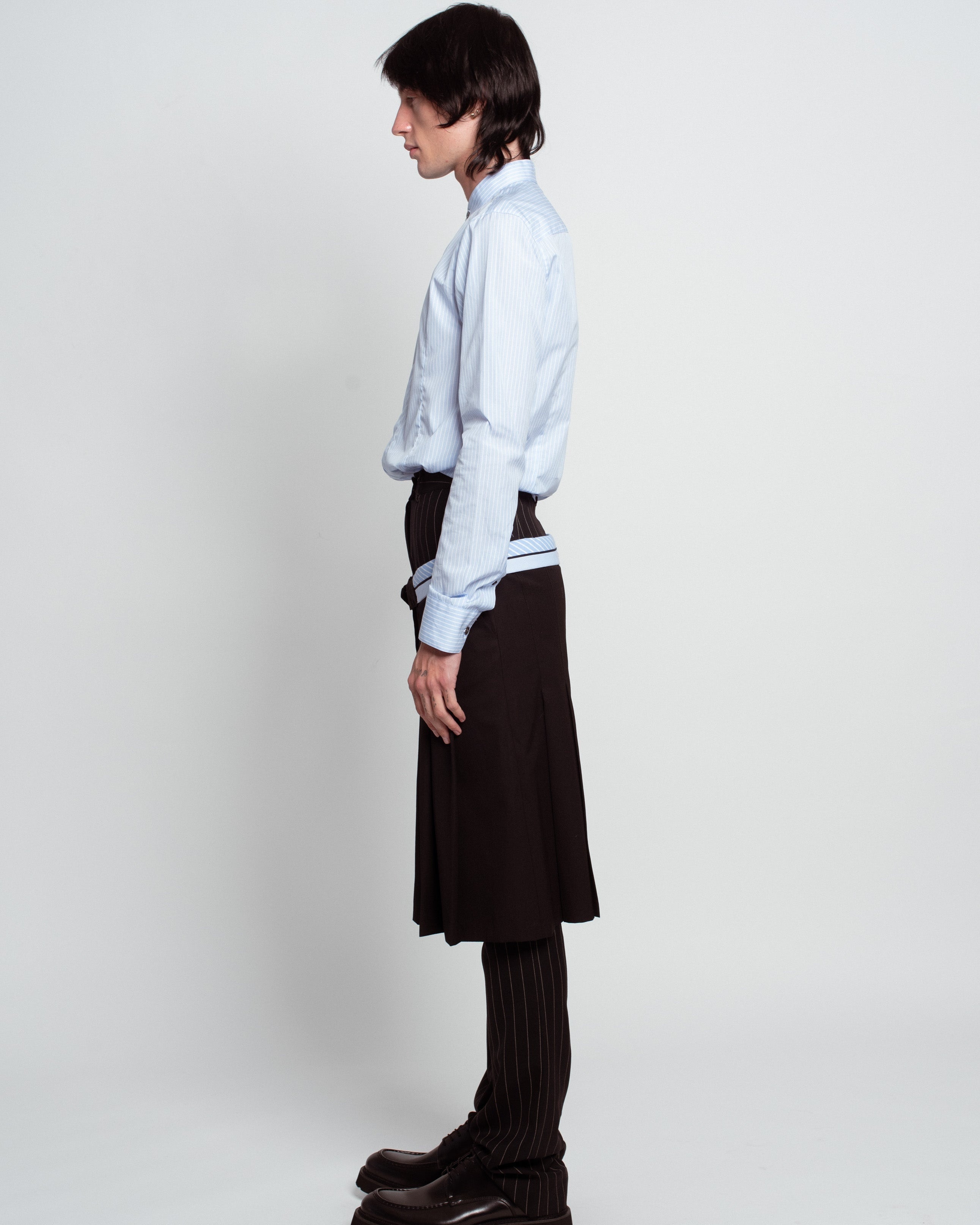 Blue Striped Band Collar Shirt in soft blue with vertical stripes, featuring a tailored fit and subtle stand-up collar, paired with pinstriped trousers and a black skirt layer, exemplifying SHAO New York bespoke tailoring and luxury designer fashion.