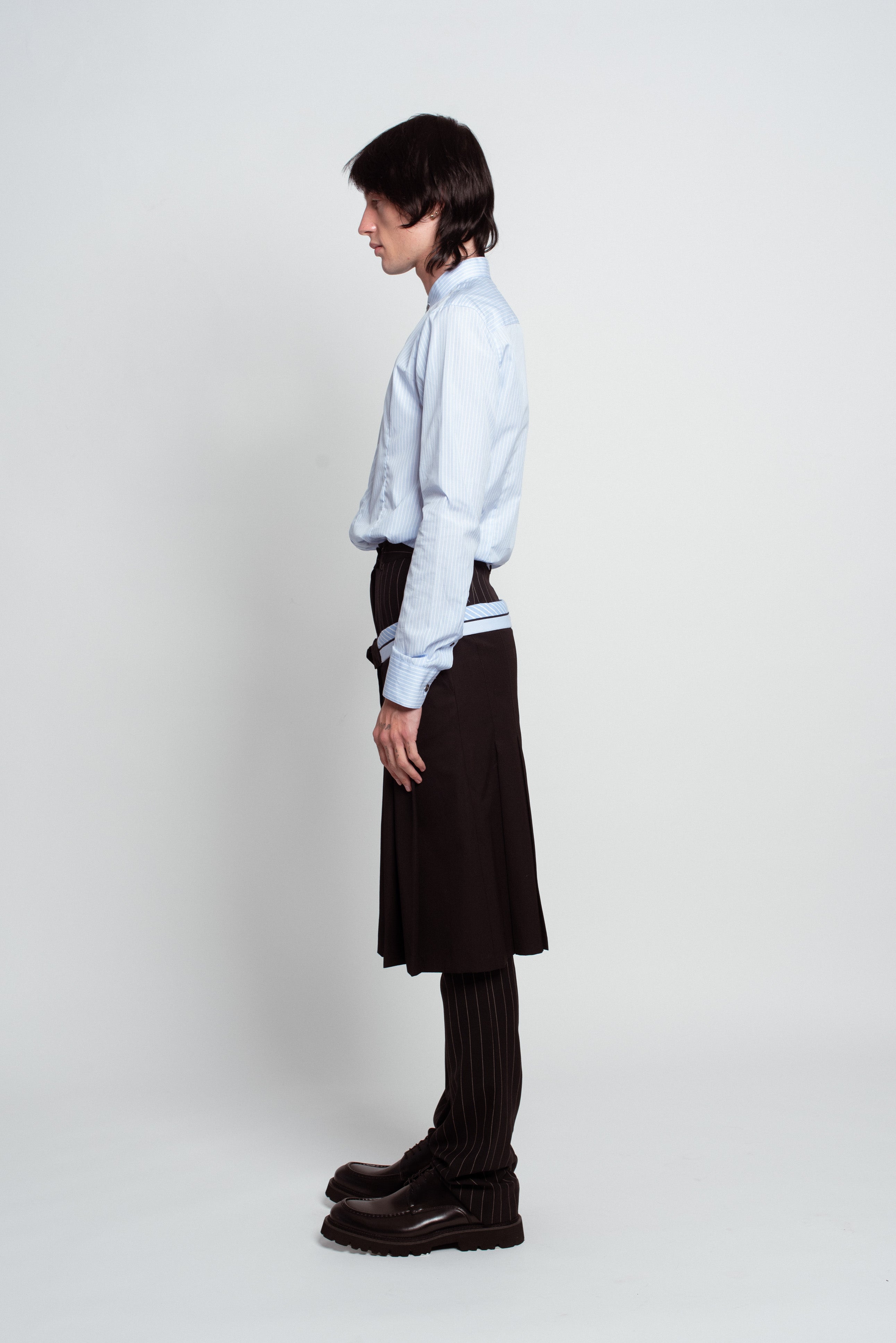 Blue Striped Band Collar Shirt in soft blue with vertical stripes, featuring a tailored fit and subtle stand-up collar, paired with pinstriped trousers and a black skirt layer, exemplifying SHAO New York bespoke tailoring and luxury designer fashion.