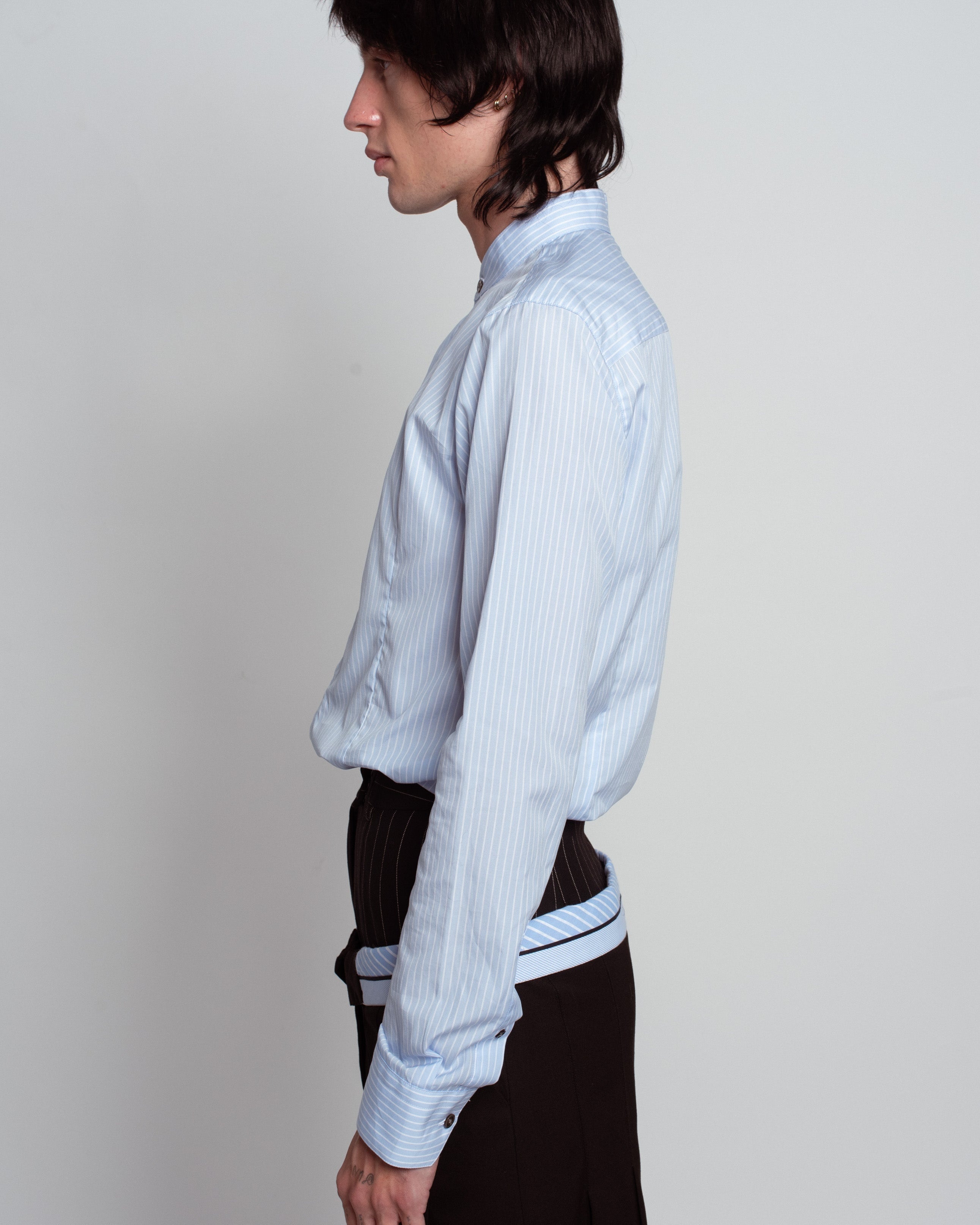 Side profile of Blue Striped Band Collar Shirt in light blue with fine vertical stripes, tailored fit, and buttoned cuffs, styled elegantly with high-waisted dark trousers, reflecting SHAO New York bespoke tailoring and luxury designer fashion.