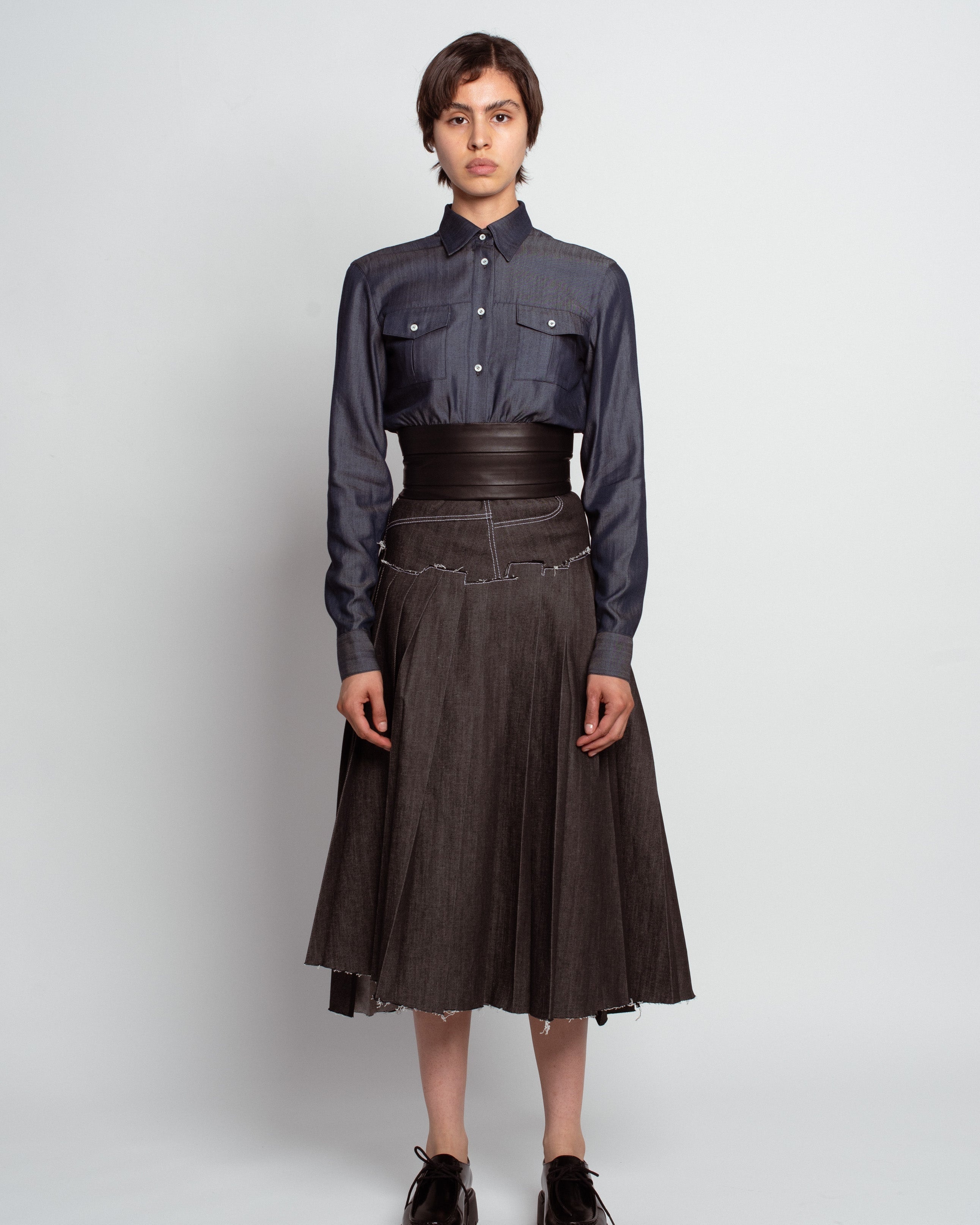Front view of a model wearing the Midnight Blue Shirt with Leather Waistband, featuring buttoned chest pockets, a tailored collar, and a wide sculptural leather waist detail, showcasing SHAO New York bespoke tailoring and luxury designer fashion.