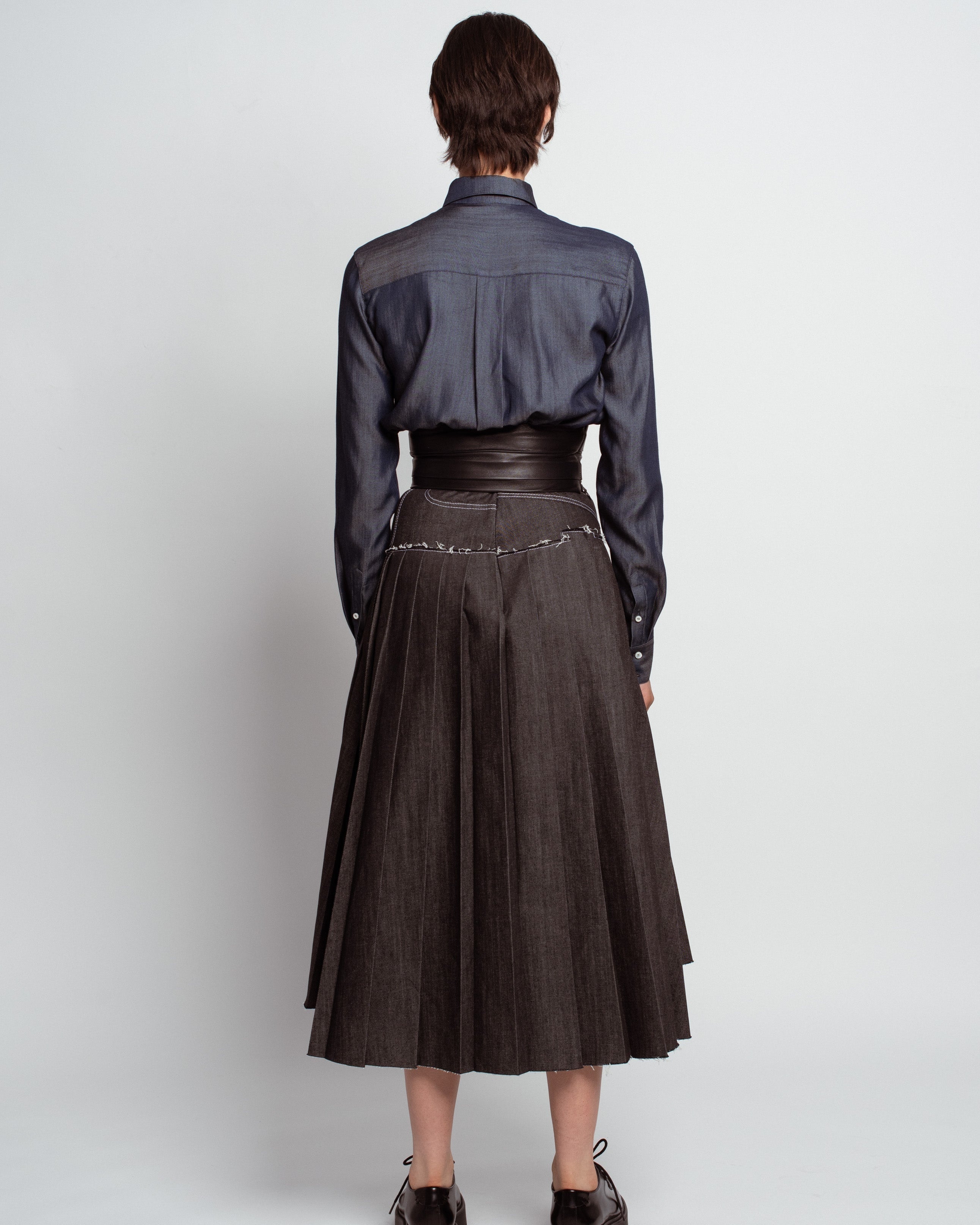 Rear view of a model wearing the Midnight Blue Shirt with Leather Waistband, highlighting the smooth satin fabric, structured yoke, leather cinched waist, and sharp tailoring by SHAO New York luxury designer fashion.
