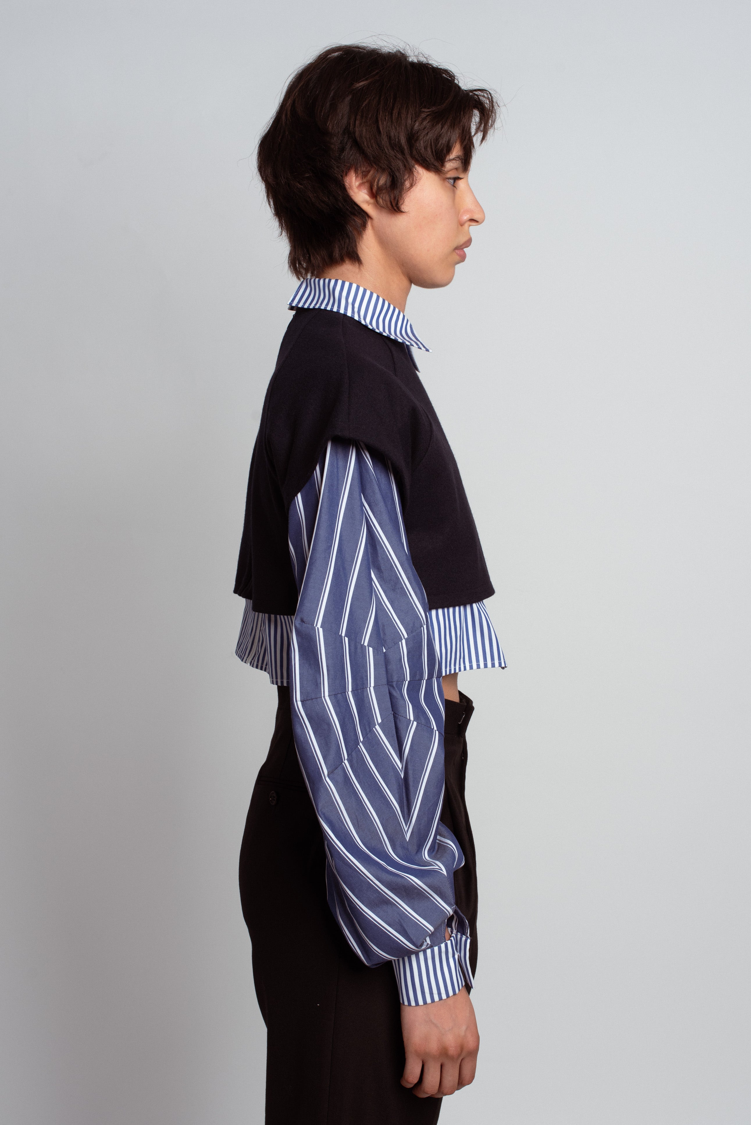 Side profile of model wearing Layered Cropped Shirt Top with navy cropped overlay and blue and white striped voluminous sleeves, featuring a pointed collar and bespoke tailoring by SHAO New York luxury designer fashion