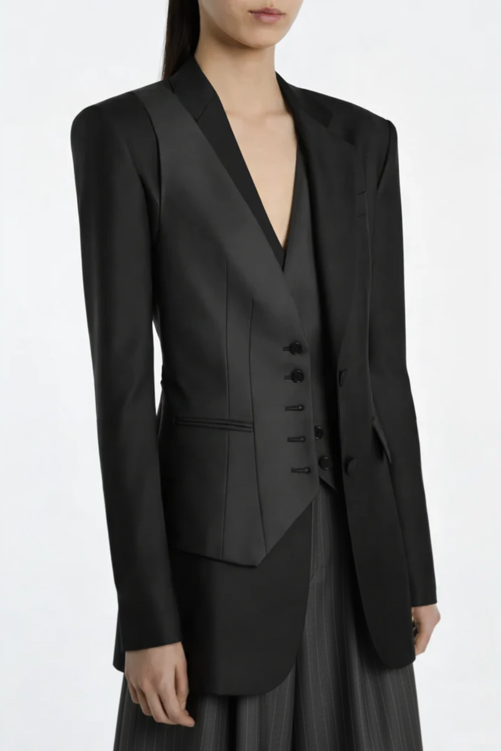 Model wearing Black Trompe L'Oeil Blazer with Satin Vest Overlay featuring sharp tailored lines and midnight black fabric, highlighting a sleek sculptural silhouette and luxury bespoke tailoring.