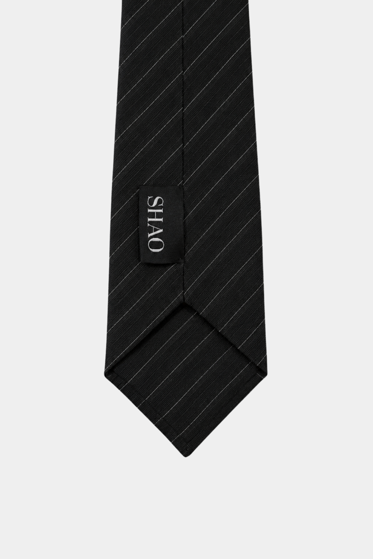 Close-up of the pointed end of the Black Pinstripe Tie 10cm featuring subtle pinstripe detailing and a branded label, reflecting SHAO New York bespoke tailoring and luxury designer fashion.