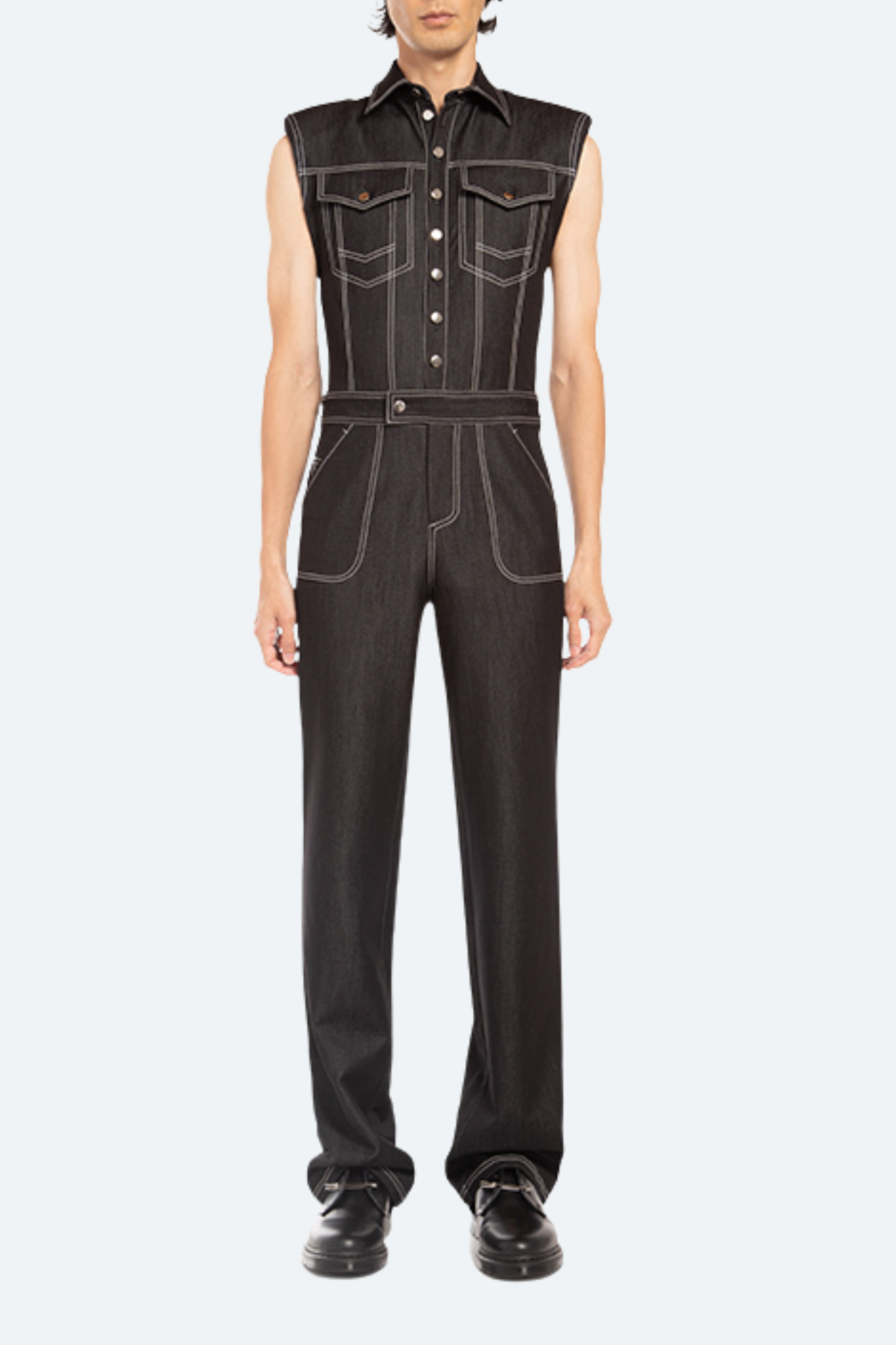 Person wearing a black denim jumpsuit on a white background