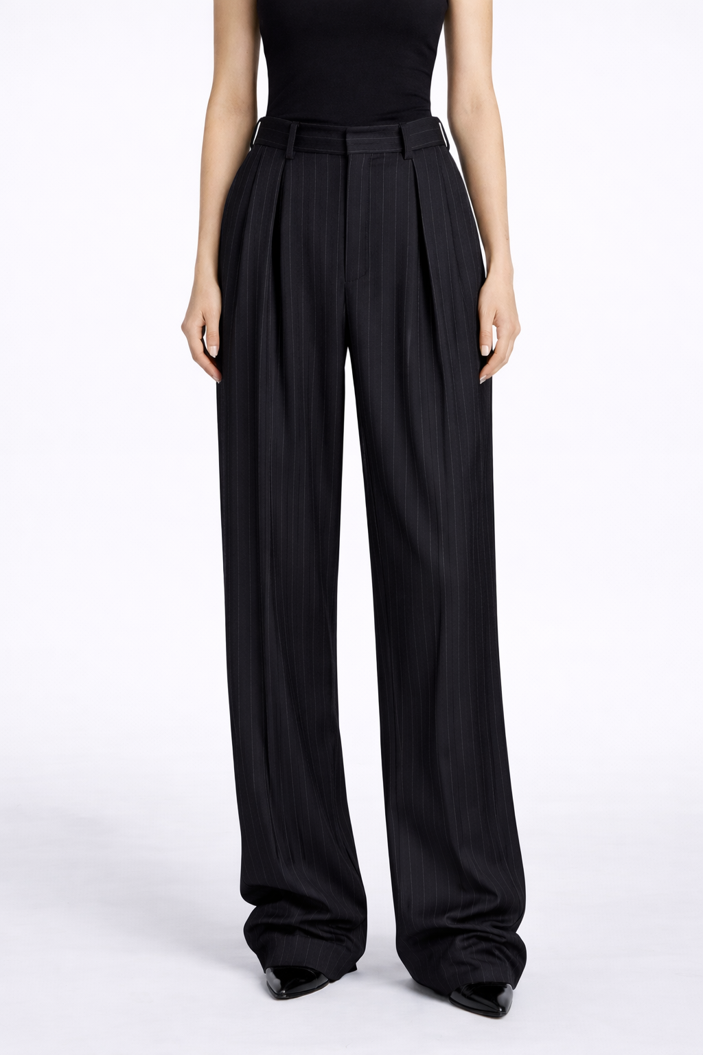 Black pleated pants worn by a person on a white background