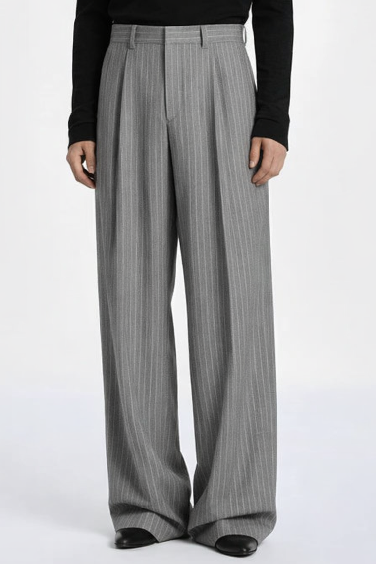 Person wearing a black turtleneck and gray pleated pants on a white background