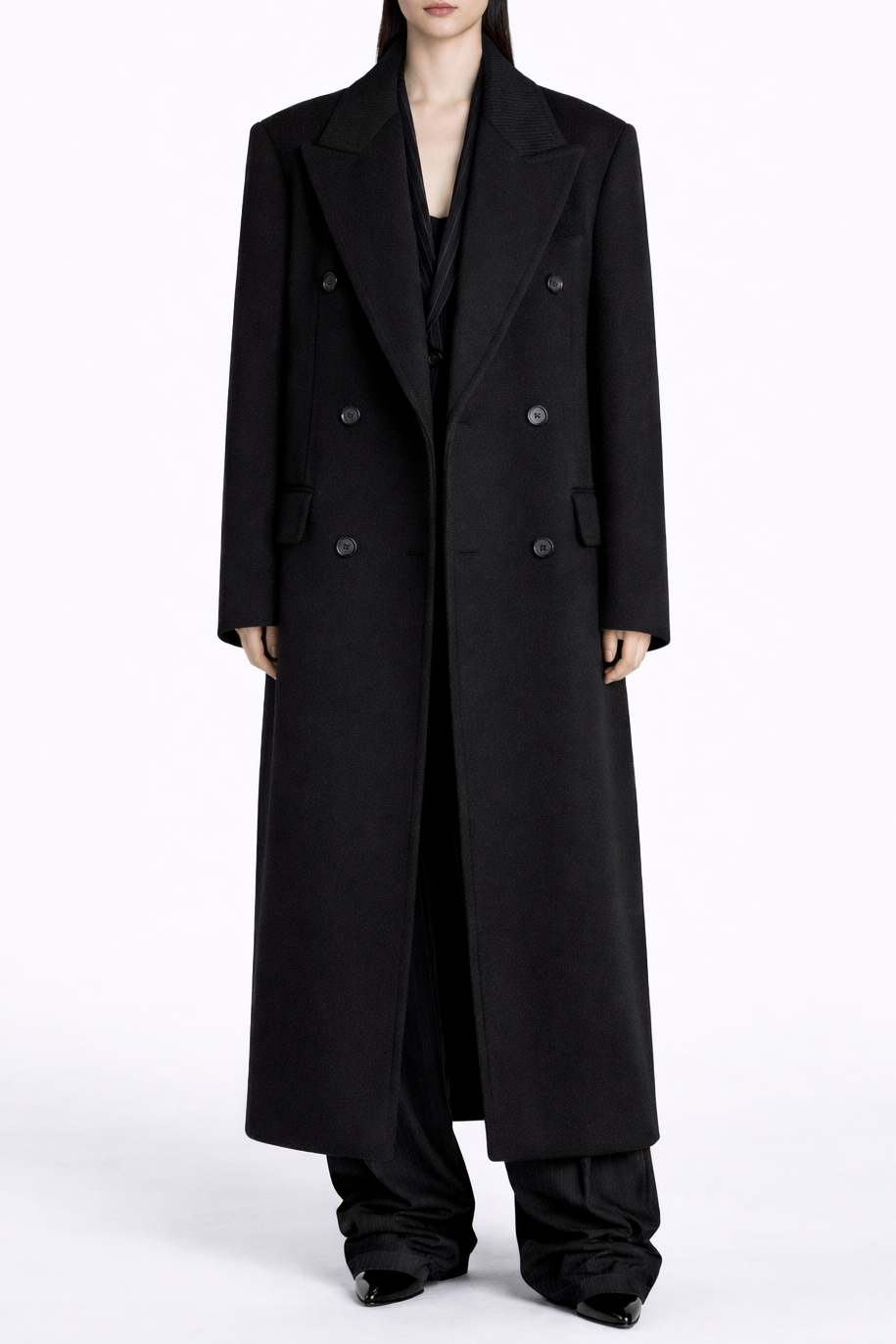 Person wearing a long black coat on a white background