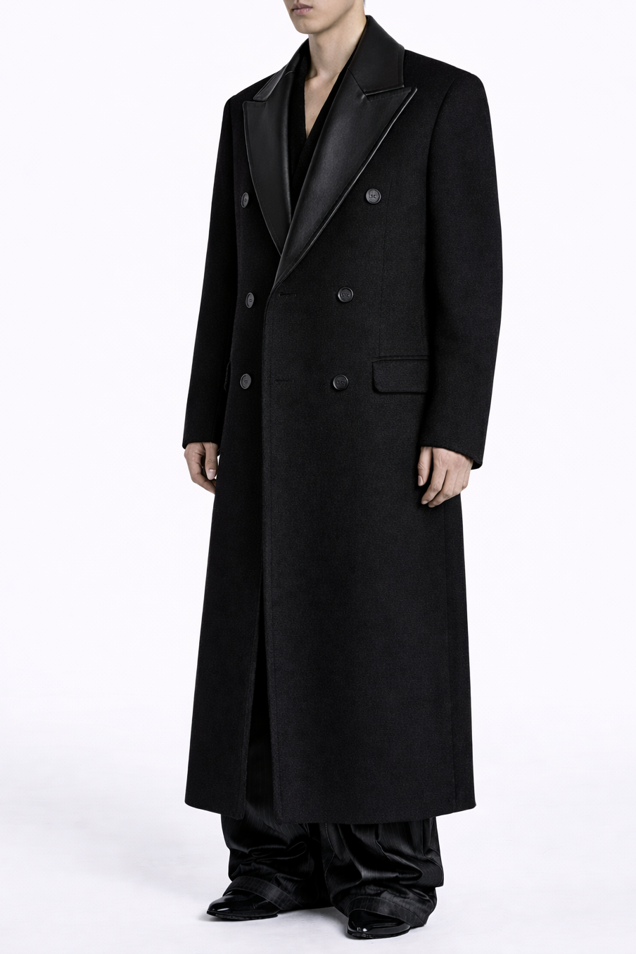 Long black coat worn by a person on a white background