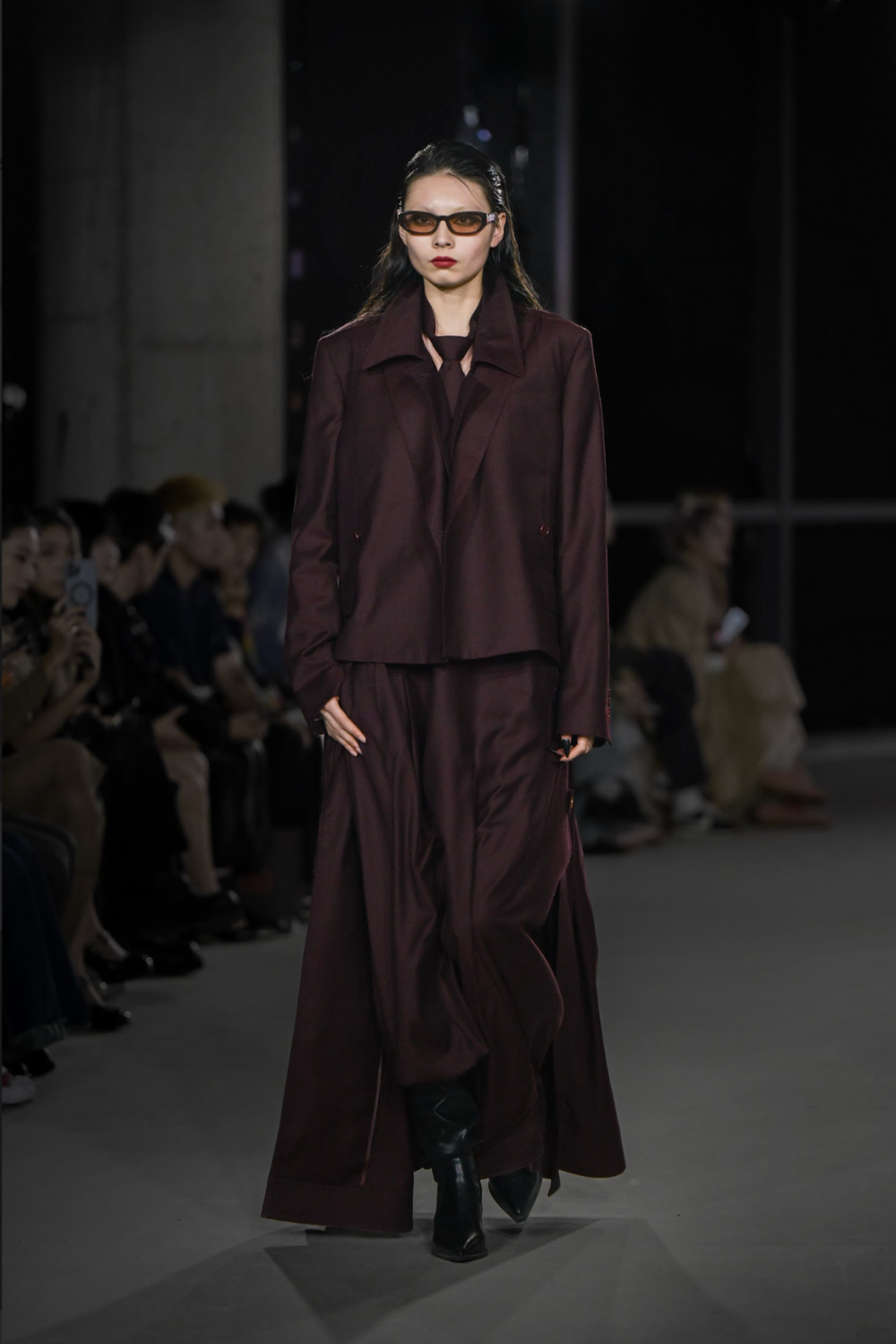 Model walking runway wearing a Burgundy Tailored Tuxedo Shirt styled with tailored wide-leg pants and tinted sunglasses, highlighting SHAO New York’s bespoke tailoring and sculptural silhouette in luxury designer fashion.